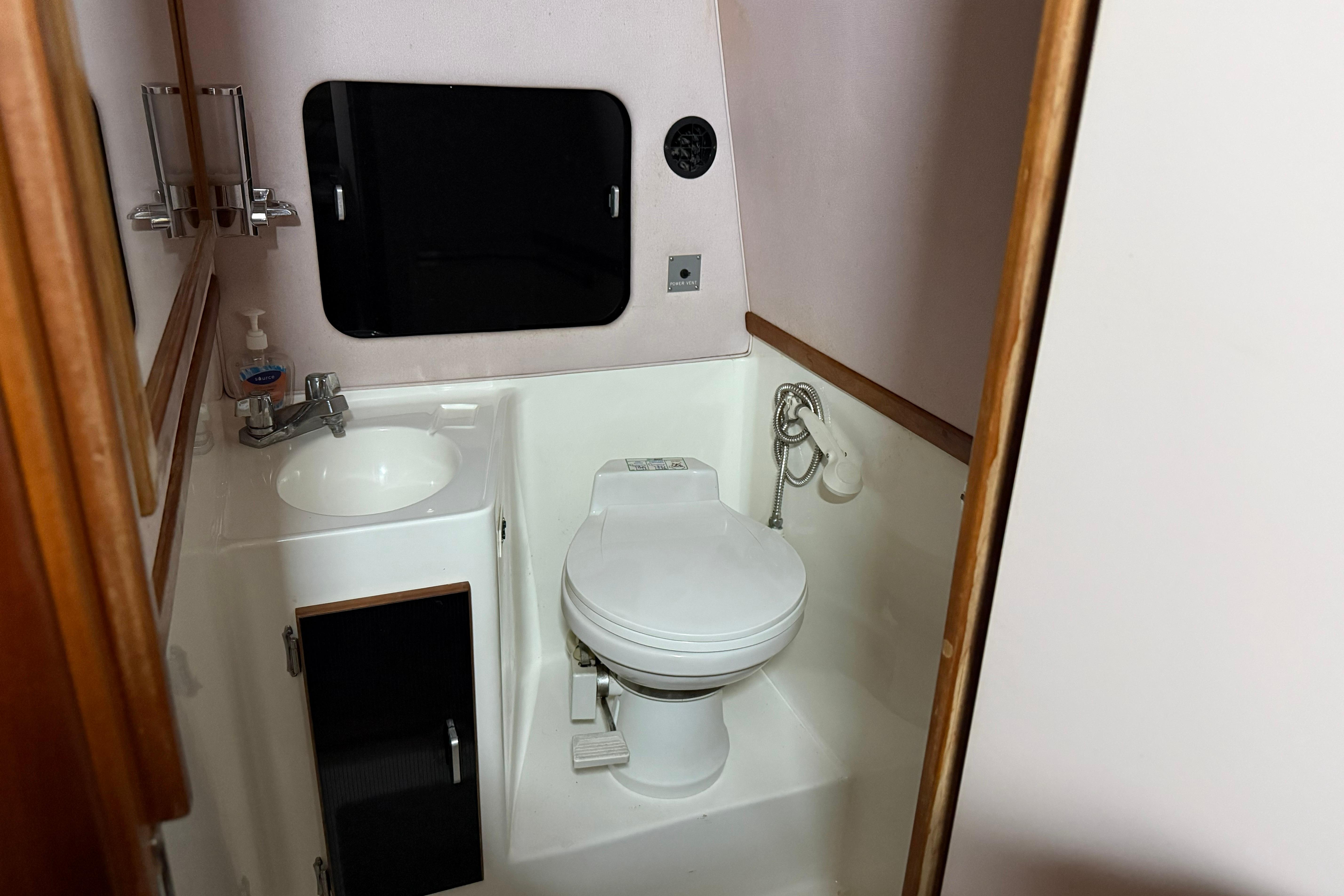 1989 Sea Ray 340 Express Cruiser bathroom with sink, toilet, and mirror.