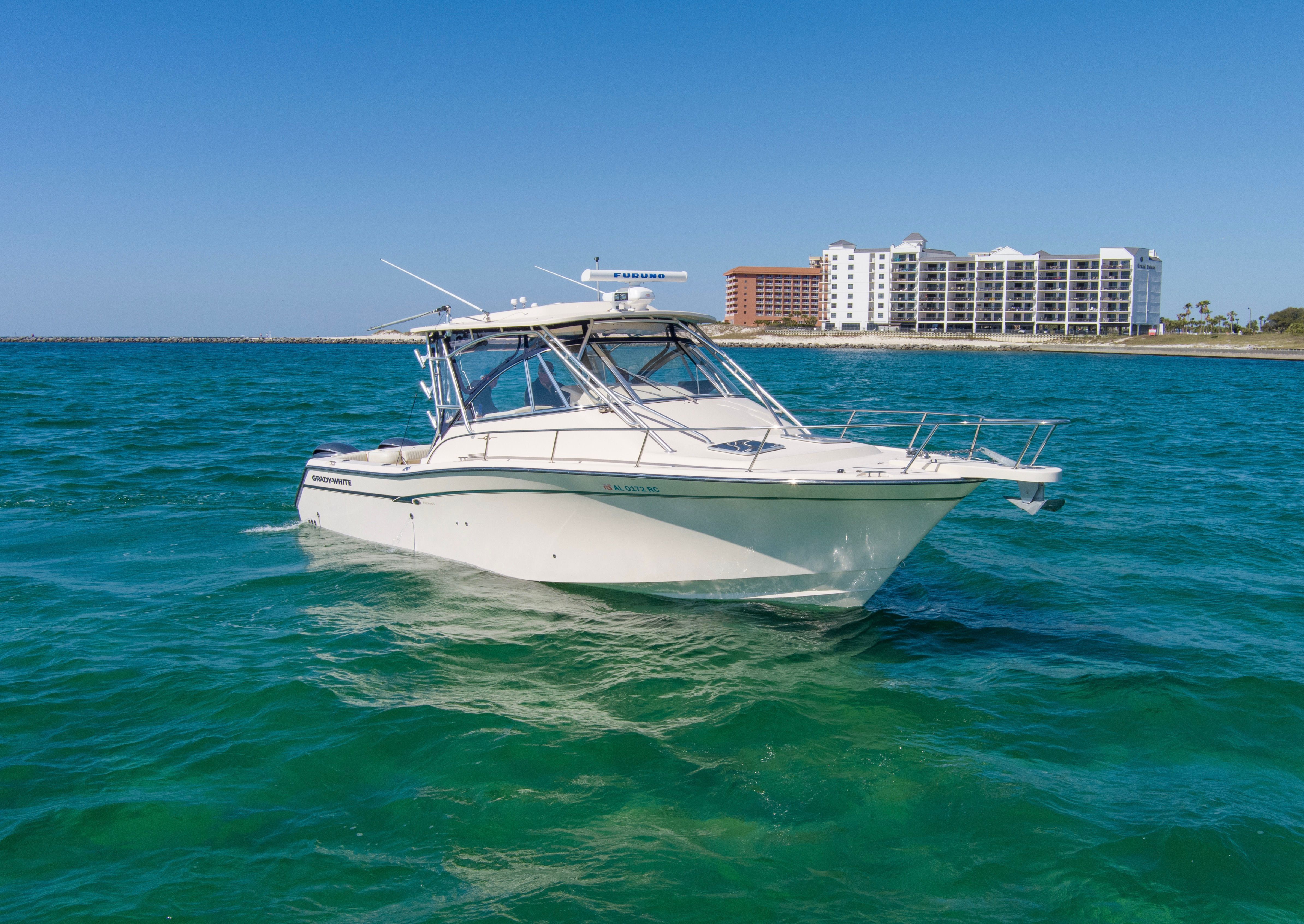 2009 Grady-White Express 330 boat on blue water near coastal building.