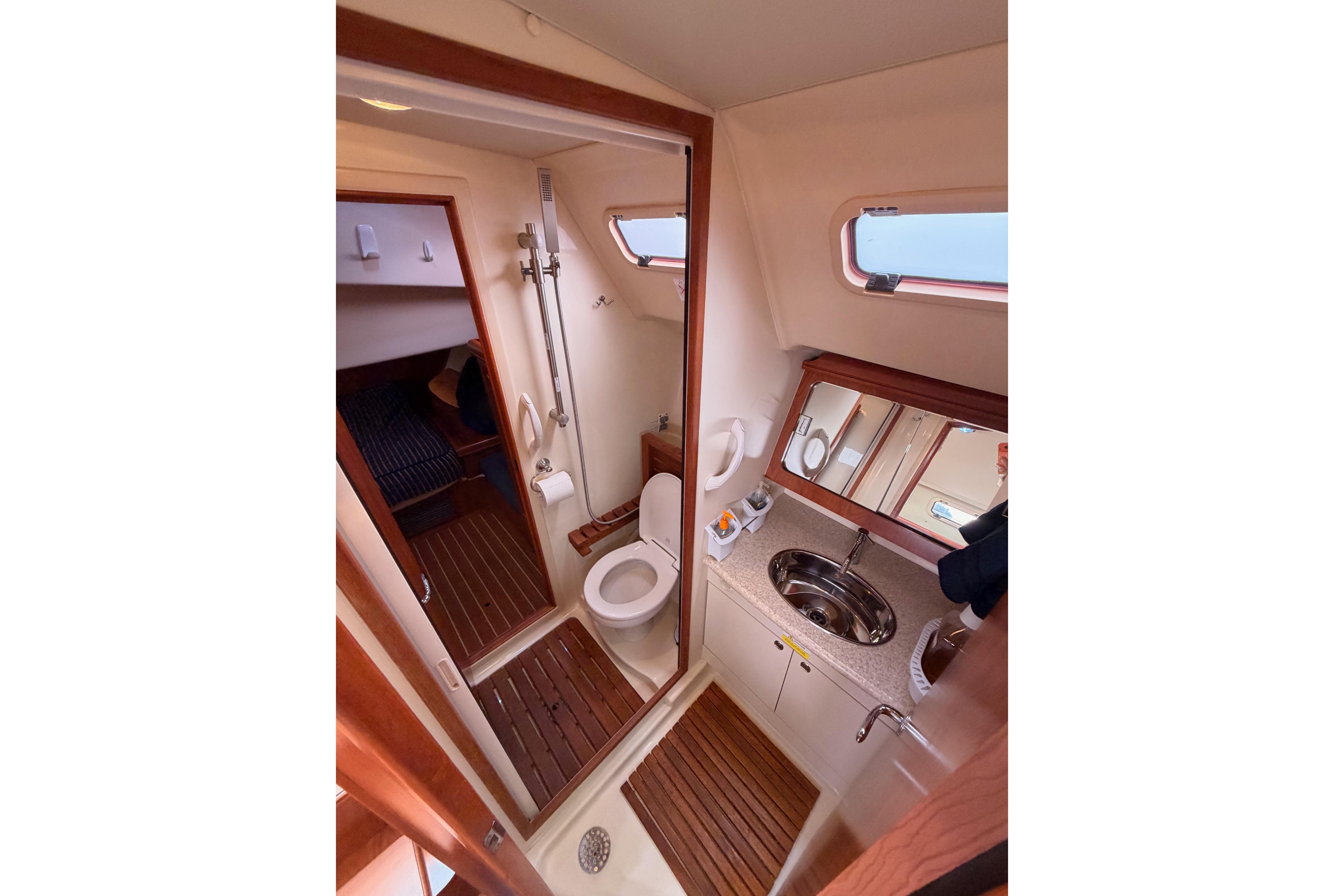 2009 Hunter 38 yacht bathroom with shower, toilet, sink, and wooden flooring.