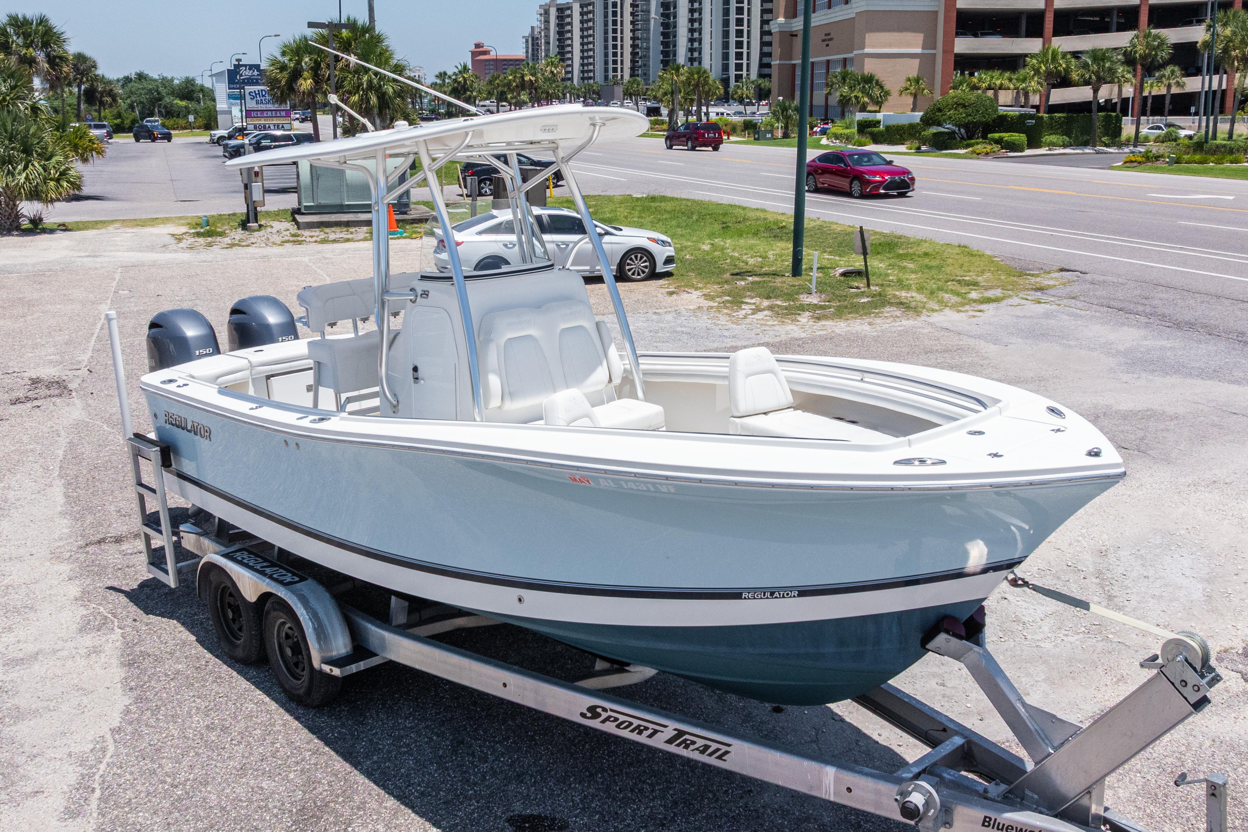 2019 Regulator 23 Center Console boat on trailer, parked near a road with palm trees.