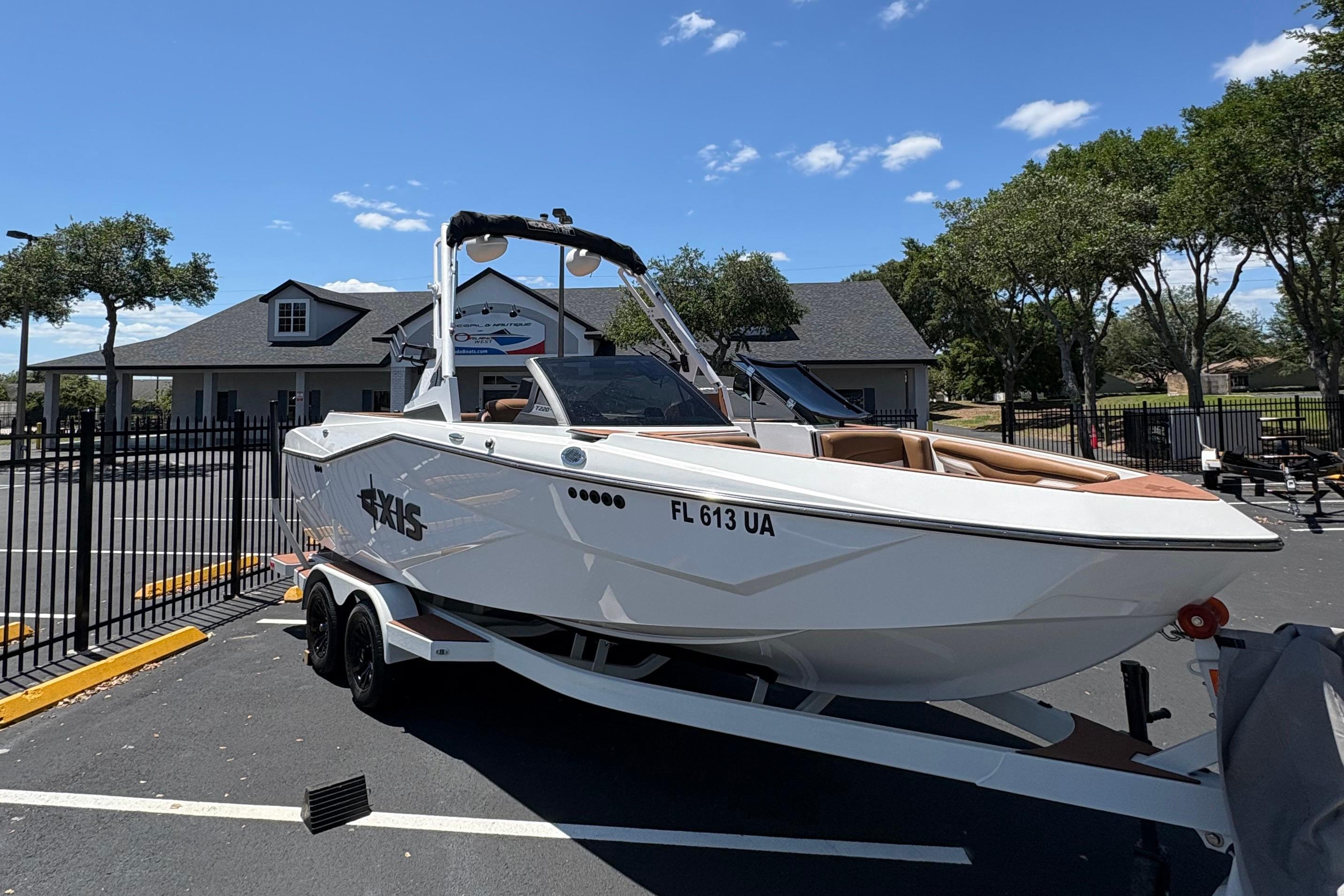 2025 Axis T220 boat on trailer in parking lot, sunny day, trees and building in background.