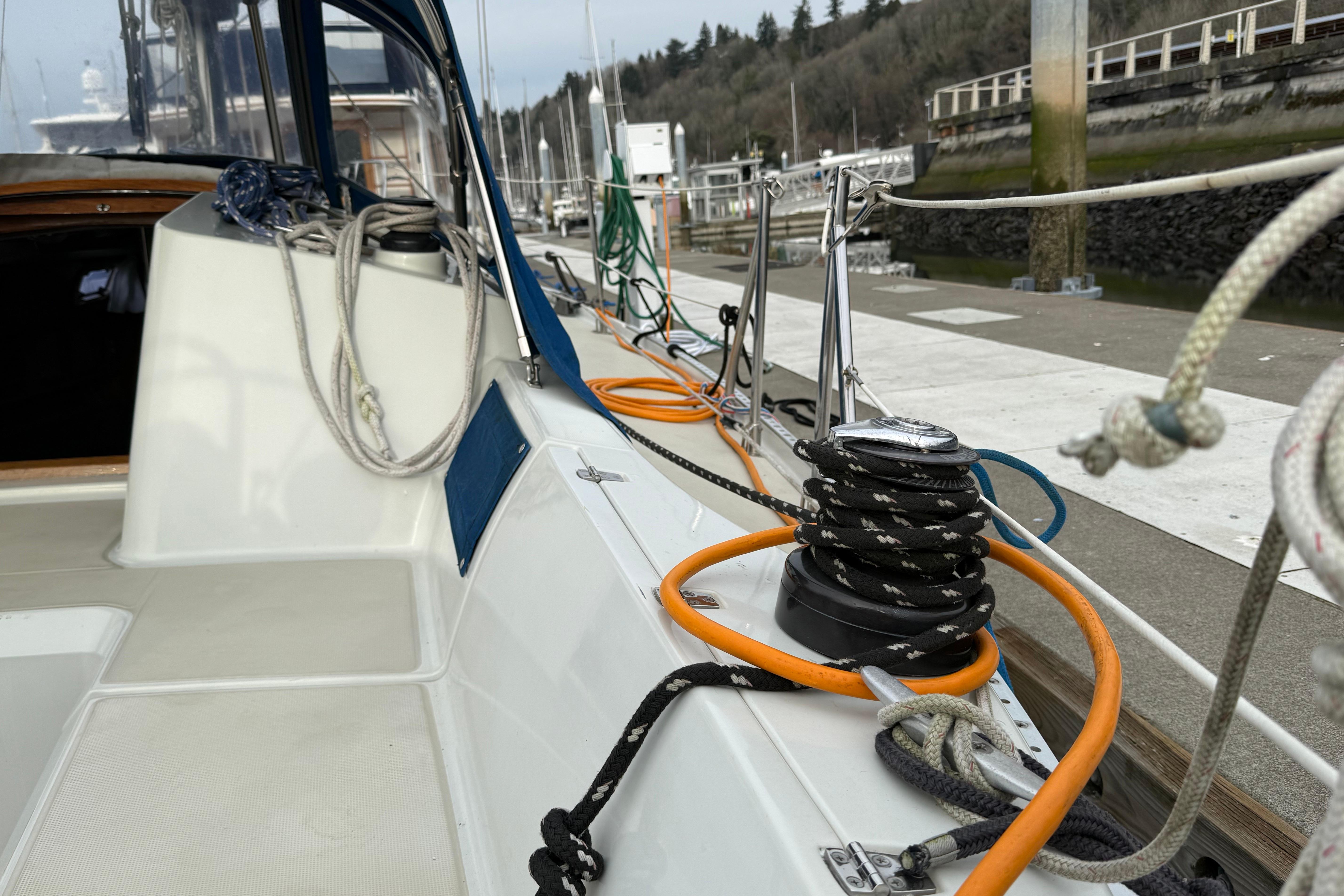1988 Ericson 32-200 sailboat docked, featuring deck ropes and winch, with marina background.