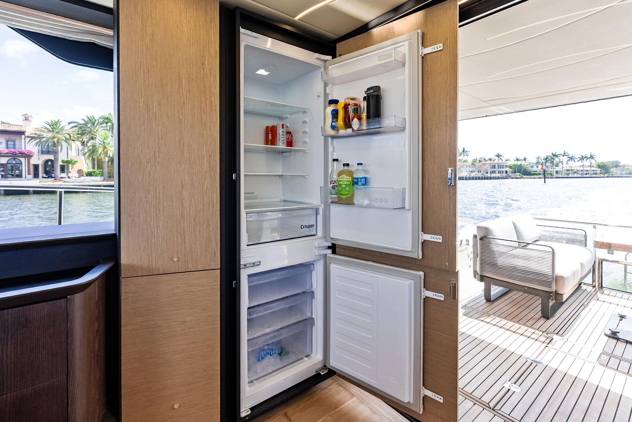 Modern kitchen on 2023 Absolute 52 FLY yacht with open fridge, scenic water view.