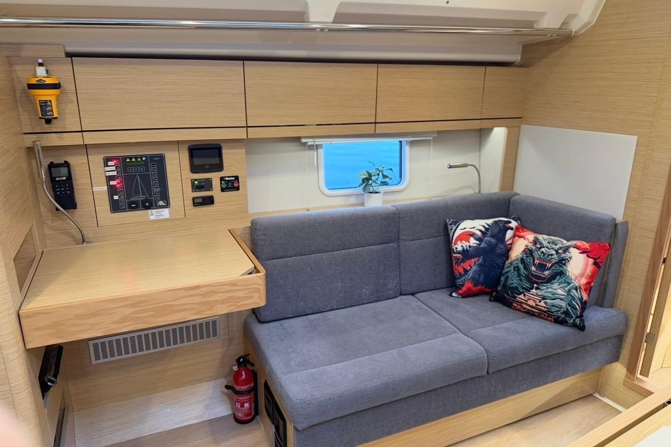 Modern interior of 2022 Hanse 418 yacht with gray sofa and colorful pillows.