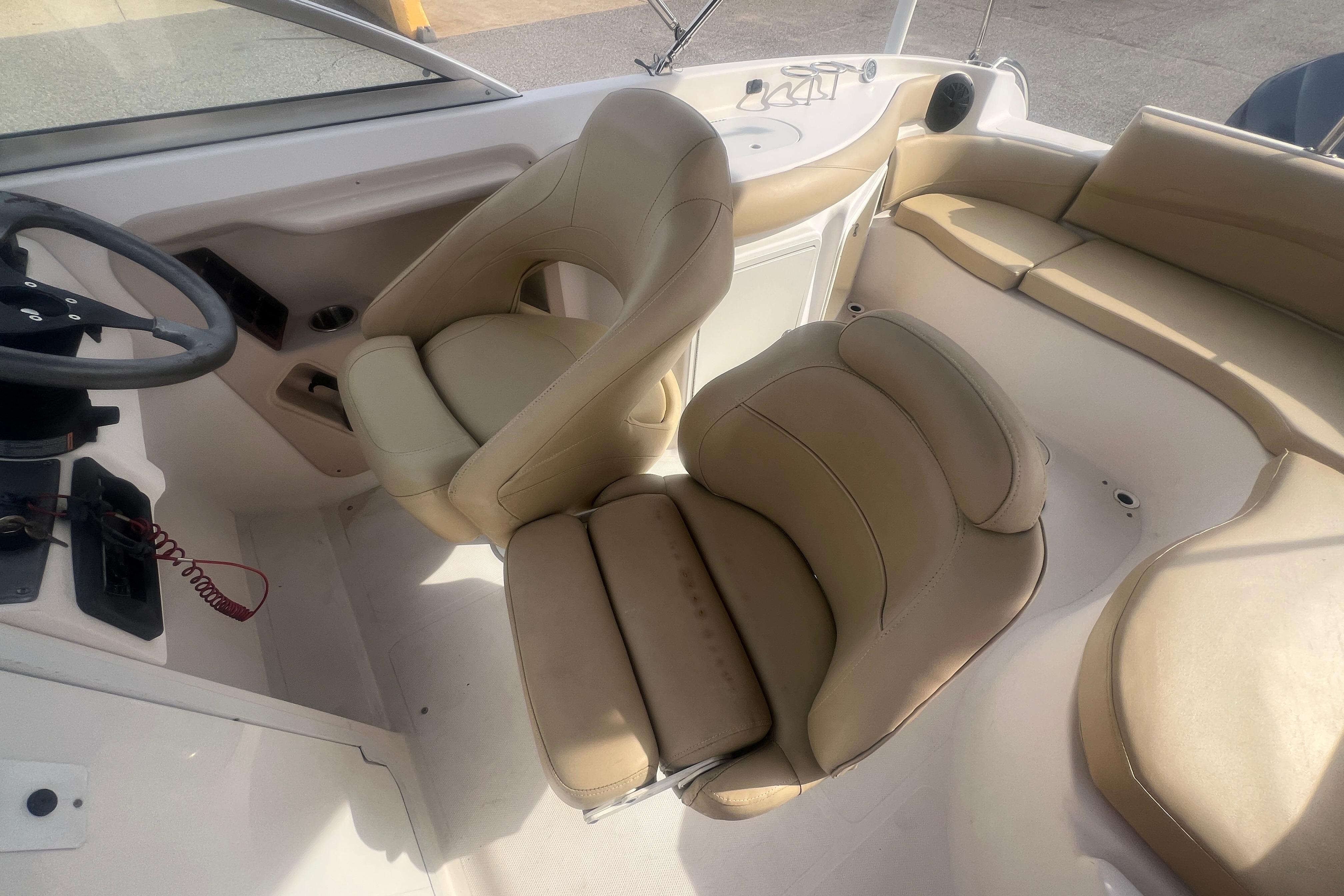 Interior of a 2002 Hurricane SunDeck 260 OB boat with beige seating and steering wheel.