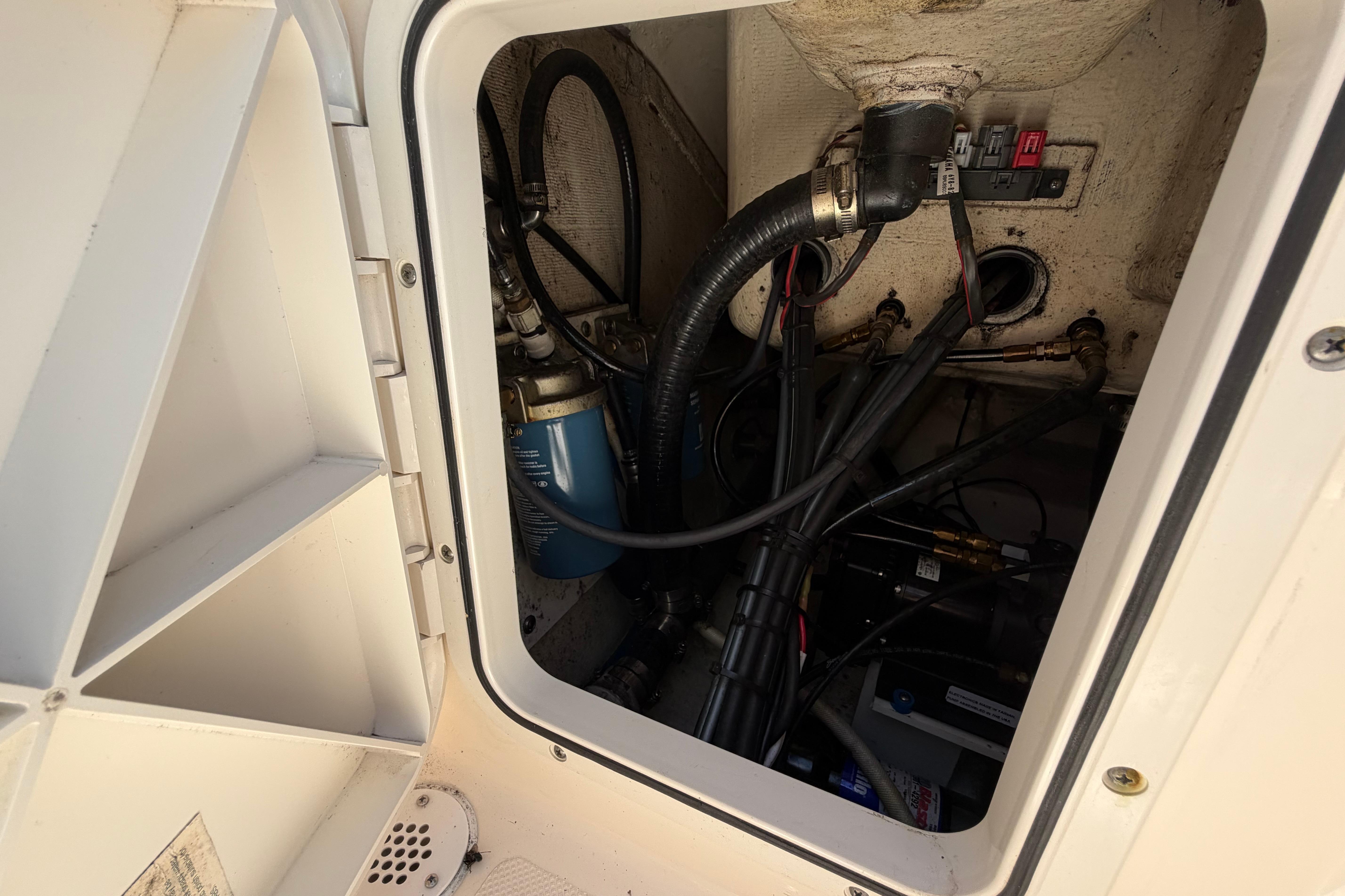Engine compartment of a 2010 Pursuit OS 255 Offshore boat, showing hoses and wiring.
