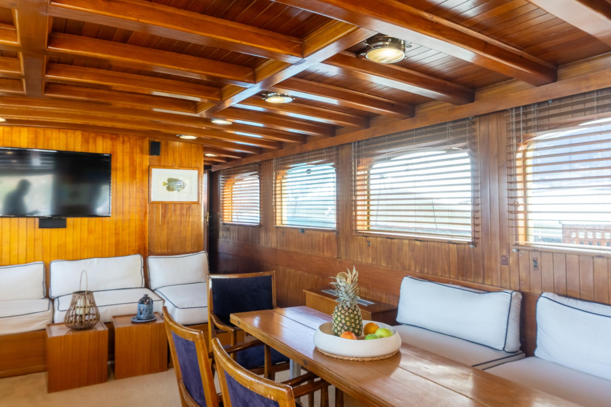 Luxurious wooden interior of a 1969 Psarros Shipyard yacht with seating and dining area.