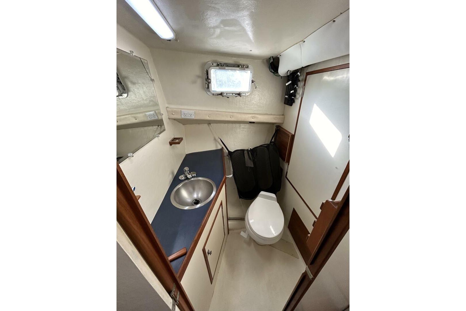 1997 Rosborough Trawler bathroom with sink, toilet, mirror, and porthole window.