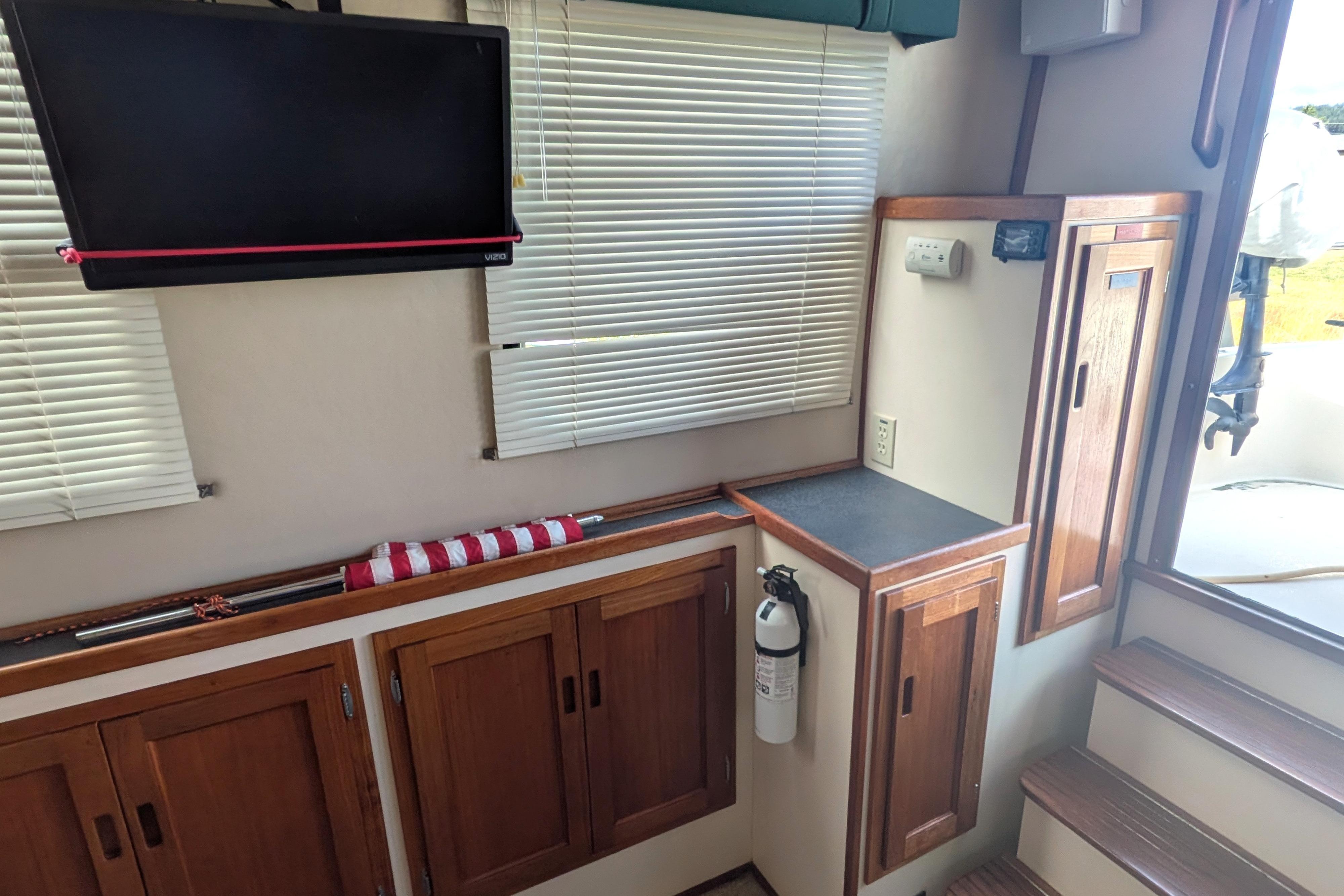 Interior of a 1998 Nordic Tug 32 with wooden cabinets, TV, and fire extinguisher.