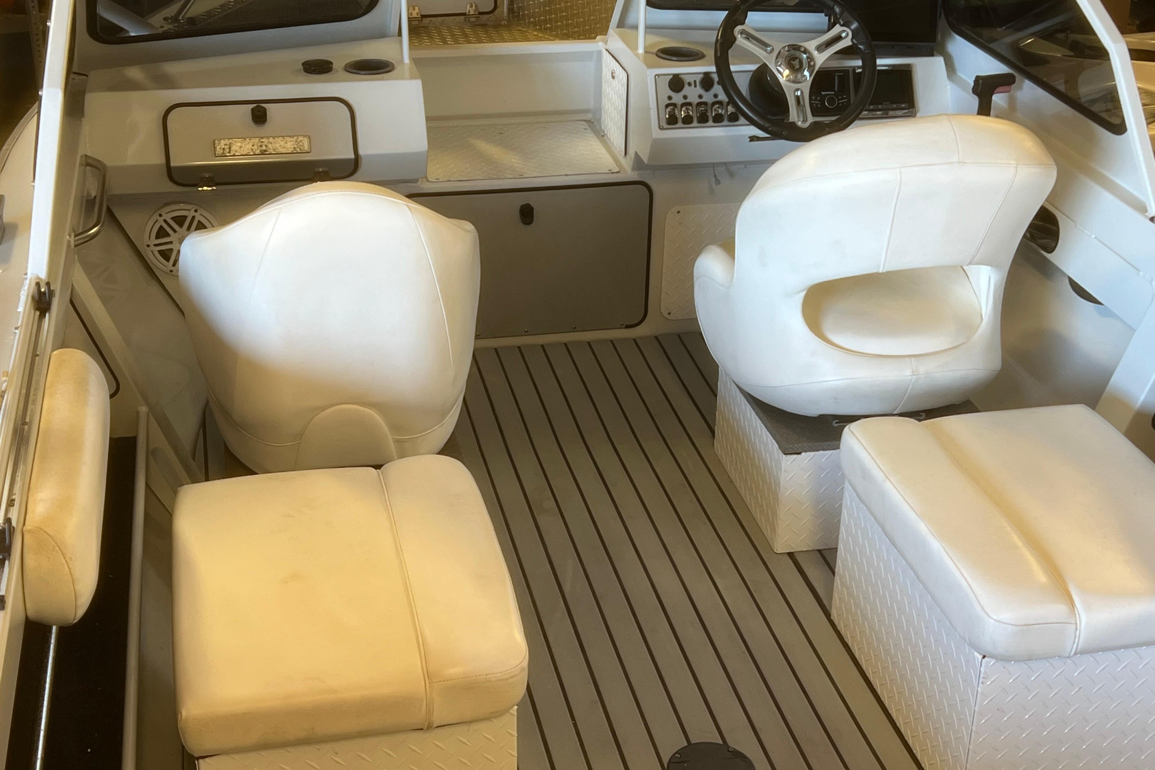 Interior of 2019 KingFisher 1825 Falcon boat with white seating and steering wheel.