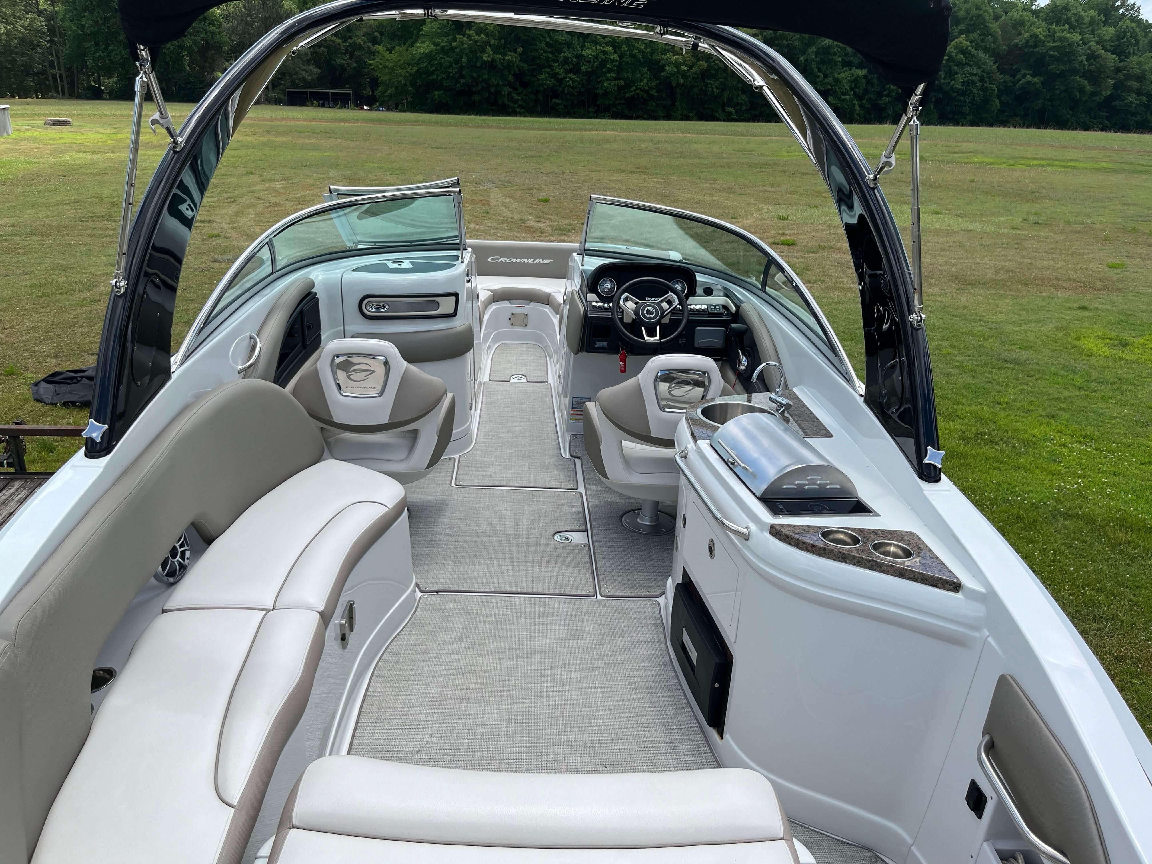 The image shows the interior of a 2019 Crownline E 285 boat with sleek seating and a helm.