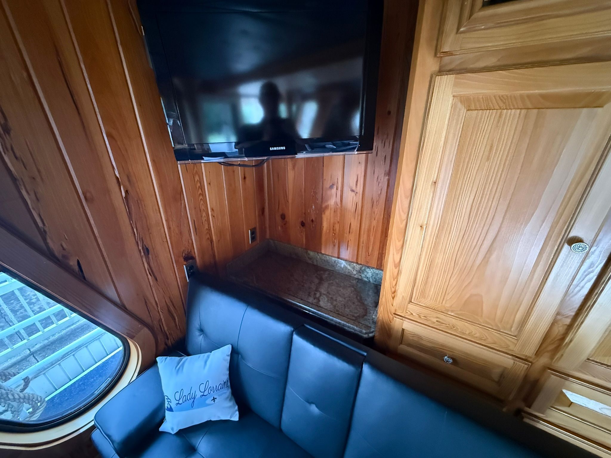 Interior with wooden walls, a sofa, and a TV mounted on the wall.