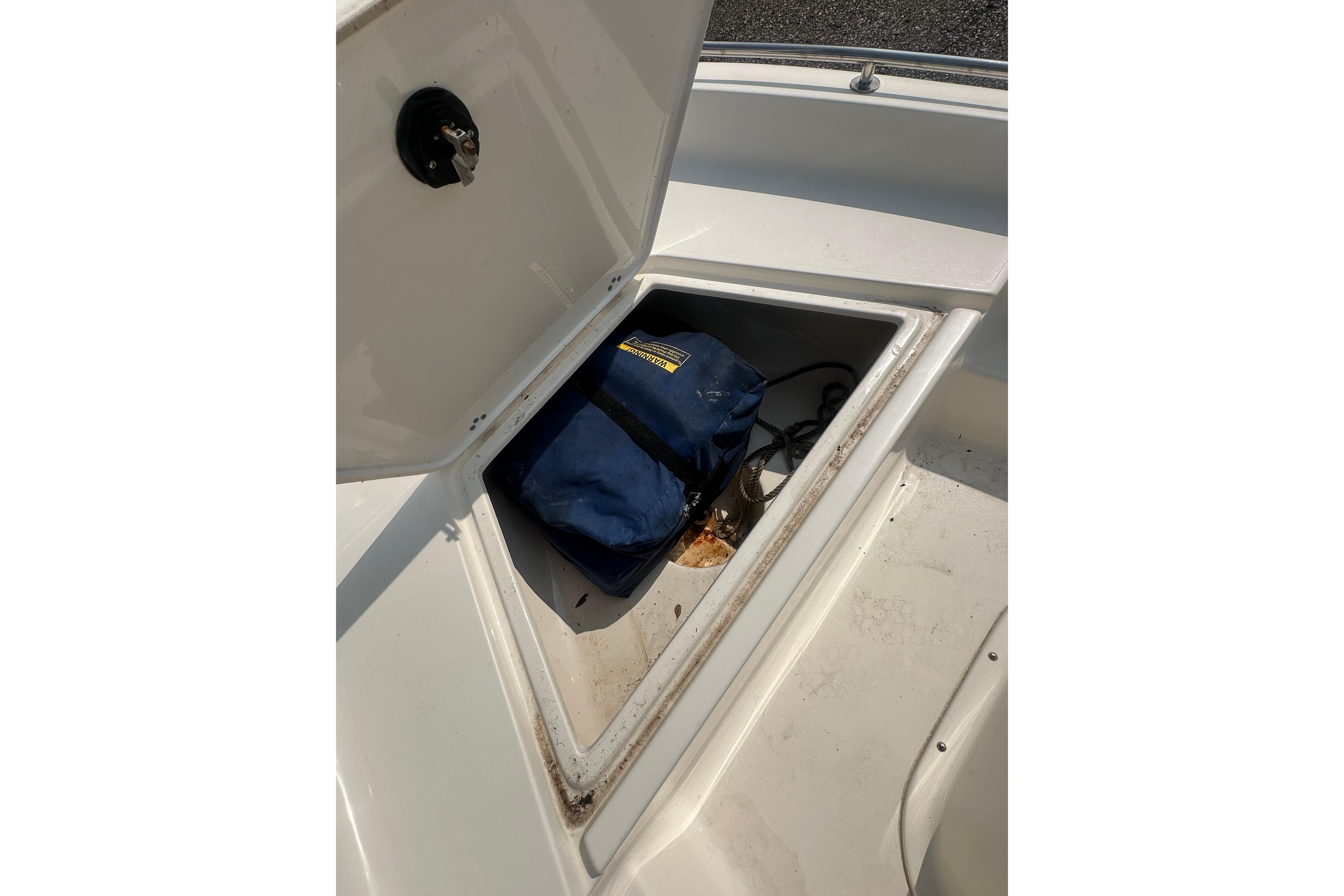 Open storage compartment on 2018 Key West 1720 Center Console boat with blue bag inside.