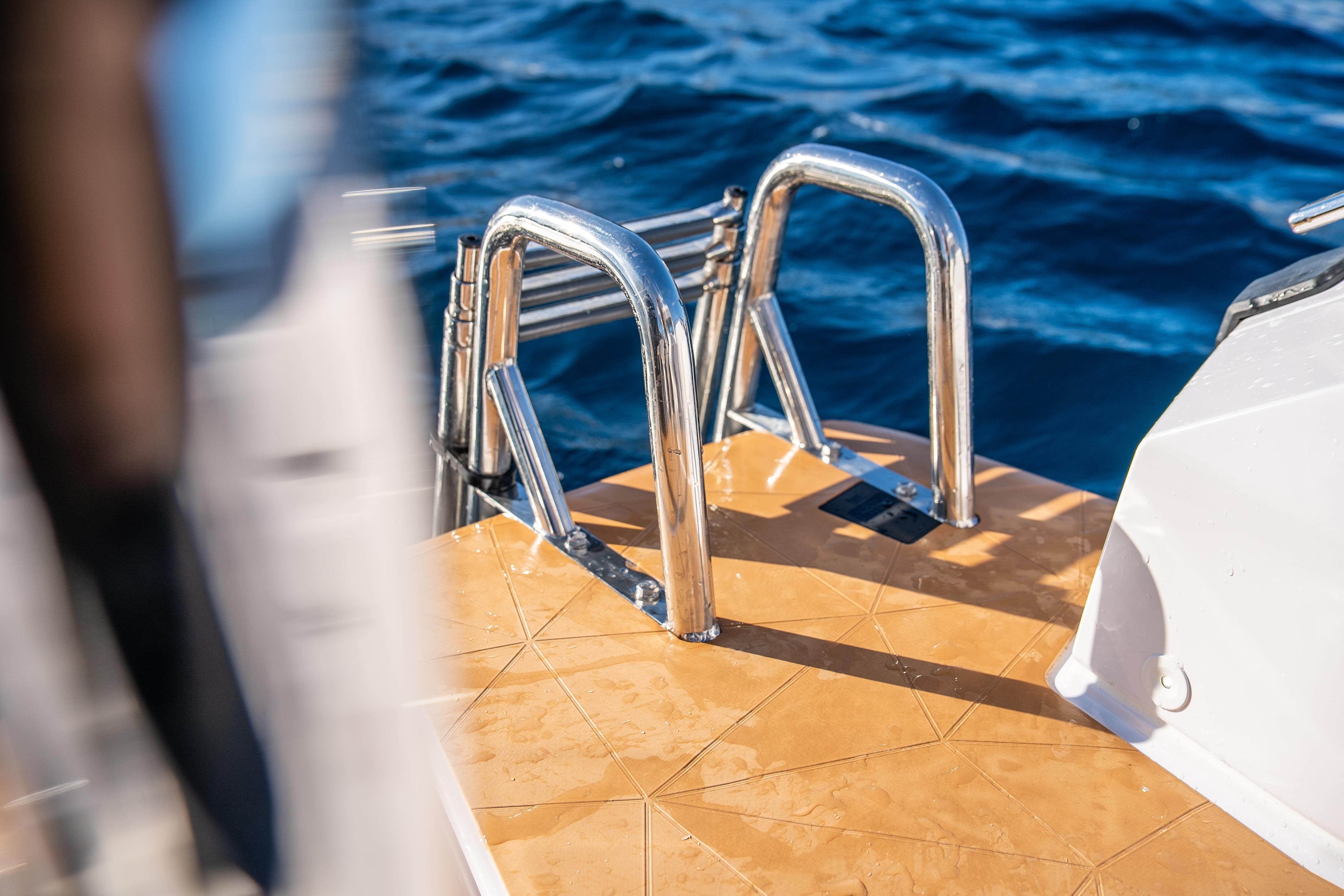 Stainless steel ladder on Axopar 29 XC Cross Cabin, 2026, against blue ocean backdrop.
