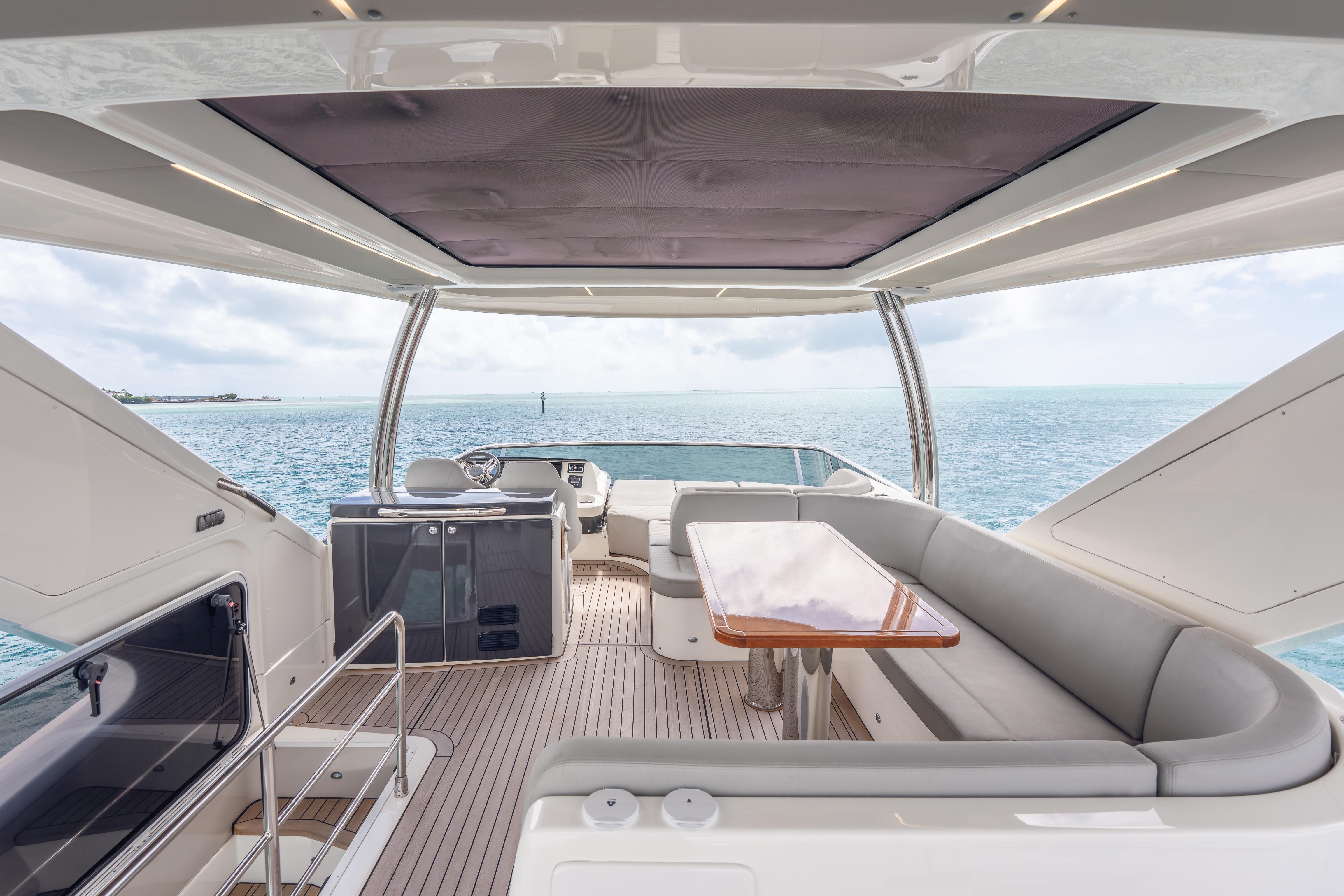 Luxurious 2019 Absolute 58 FLY yacht interior with ocean view, featuring elegant seating and table.