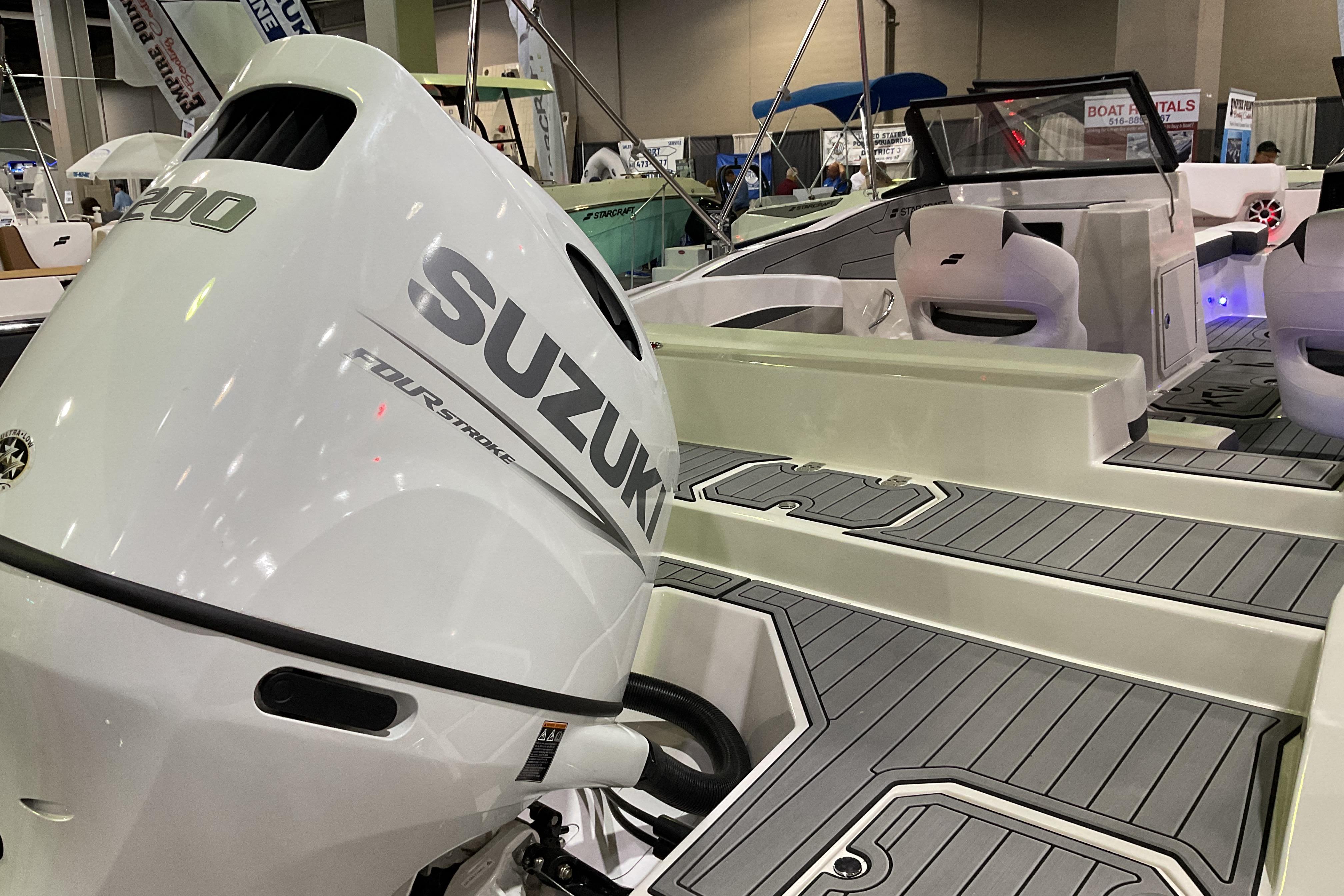 2026 Starcraft SVX 210 DC OB boat with Suzuki outboard motor at a boat show.