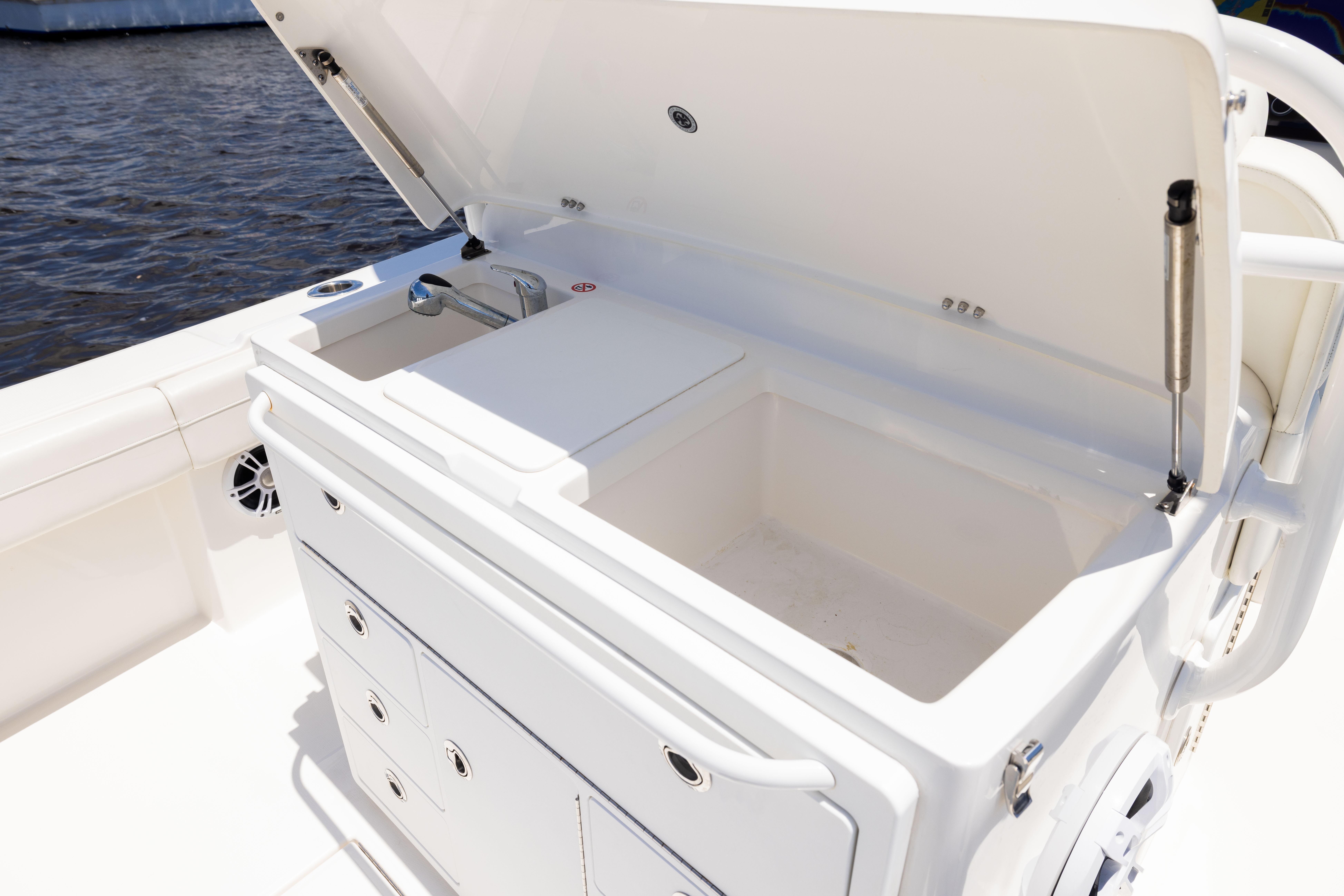 2024 Regulator 34 boat with open storage compartment and sink, docked by the water.