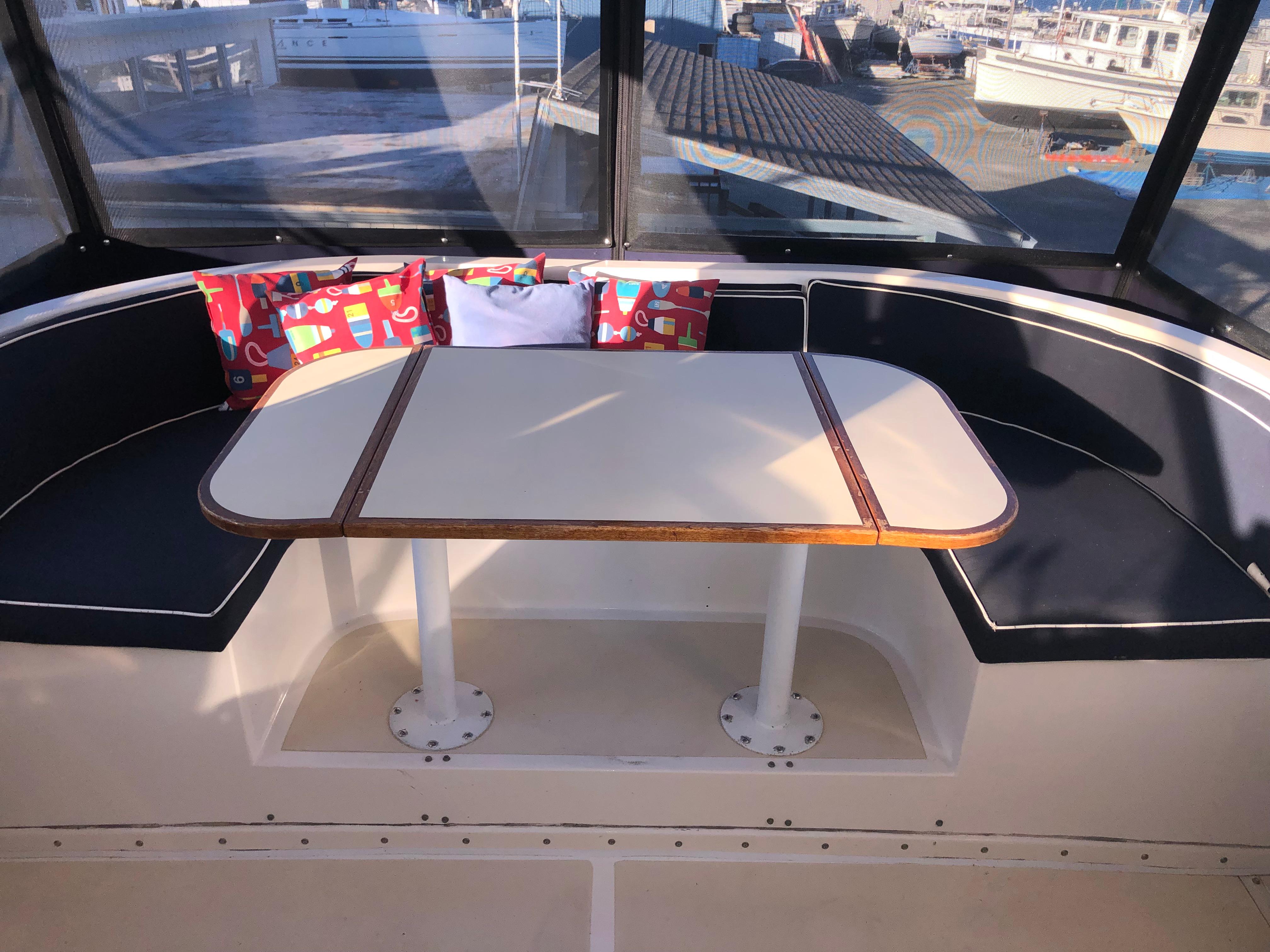1987 Kadey-Krogen Silhouette boat interior with cushioned seating and table, featuring colorful pillows.