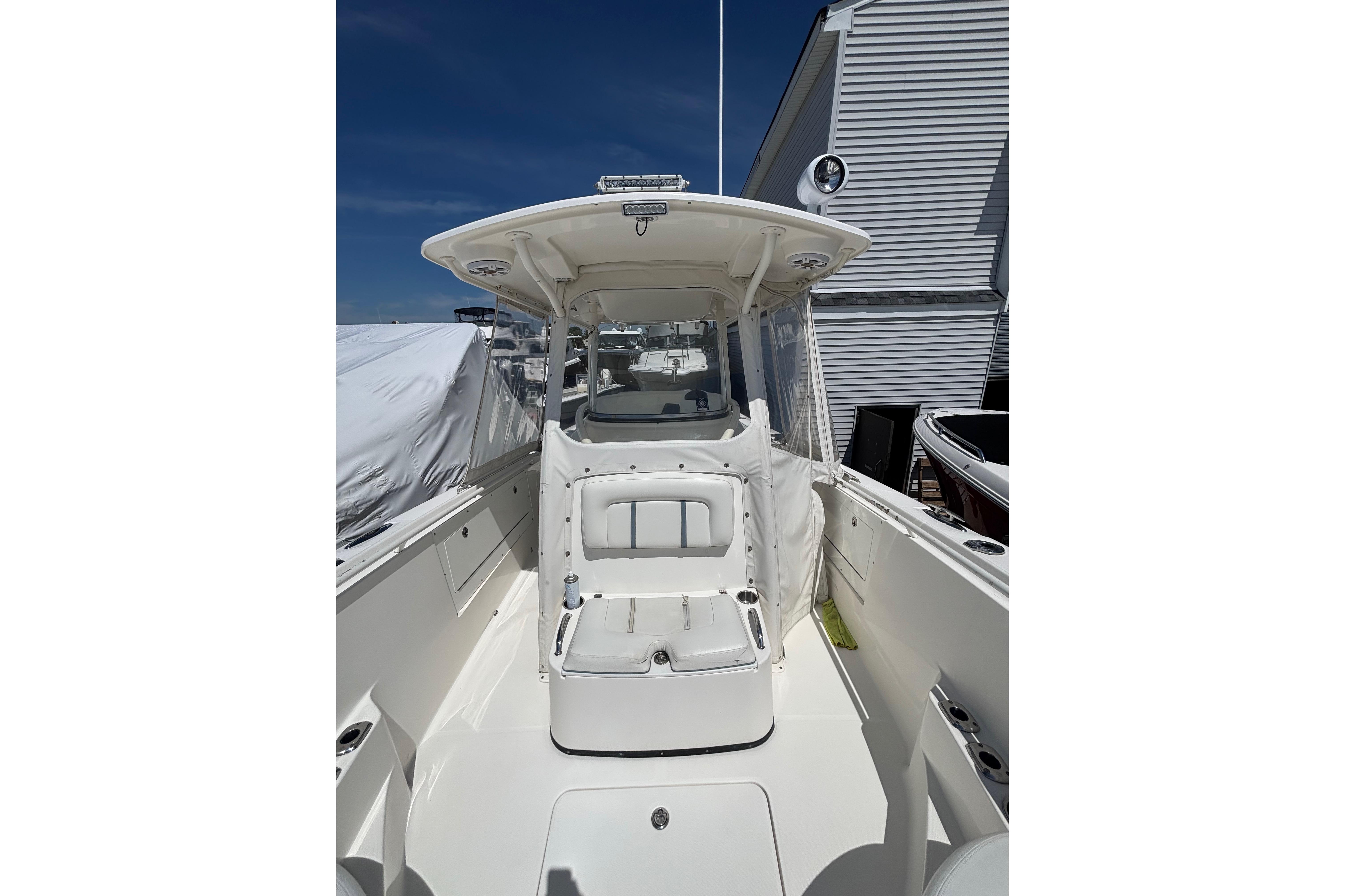 2006 Edgewater 318CC boat with white interior, docked near a building under clear blue sky.