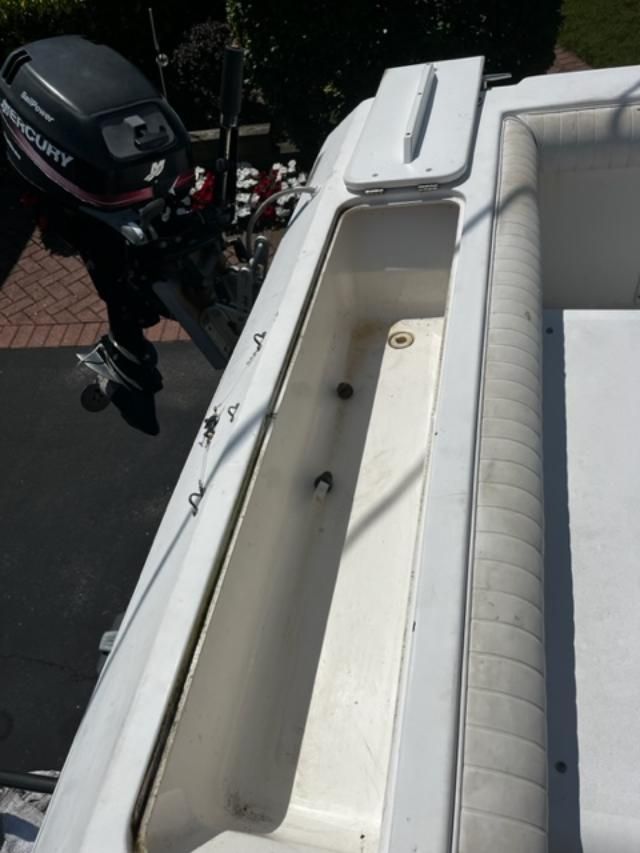 A 1998 Sport-Craft 252 Sport Fish with a Mercury outboard motor. It shows an open storage compartment.