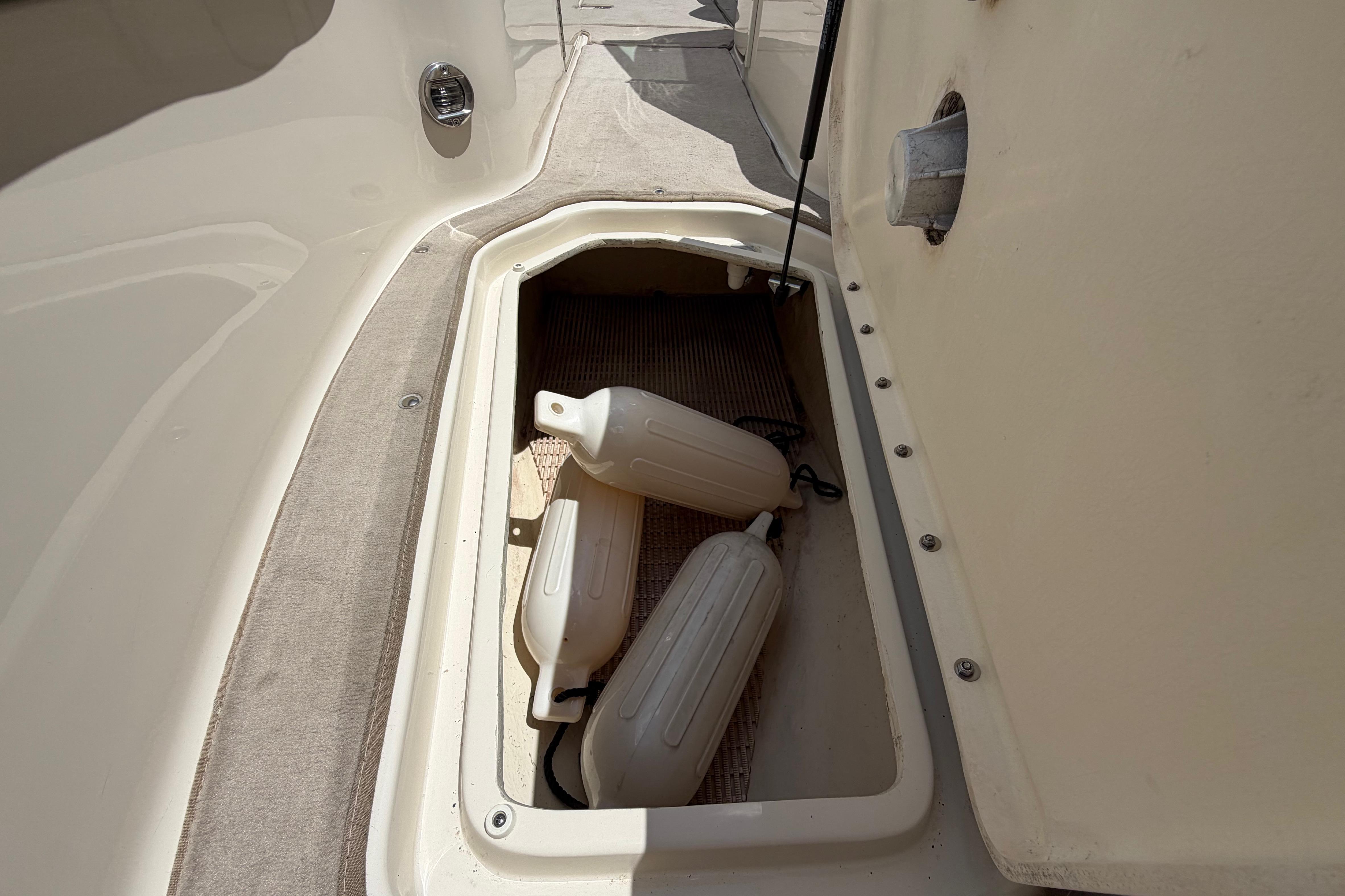 Storage compartment on a 2004 Sea Ray 240 Sundeck with boat fenders inside.