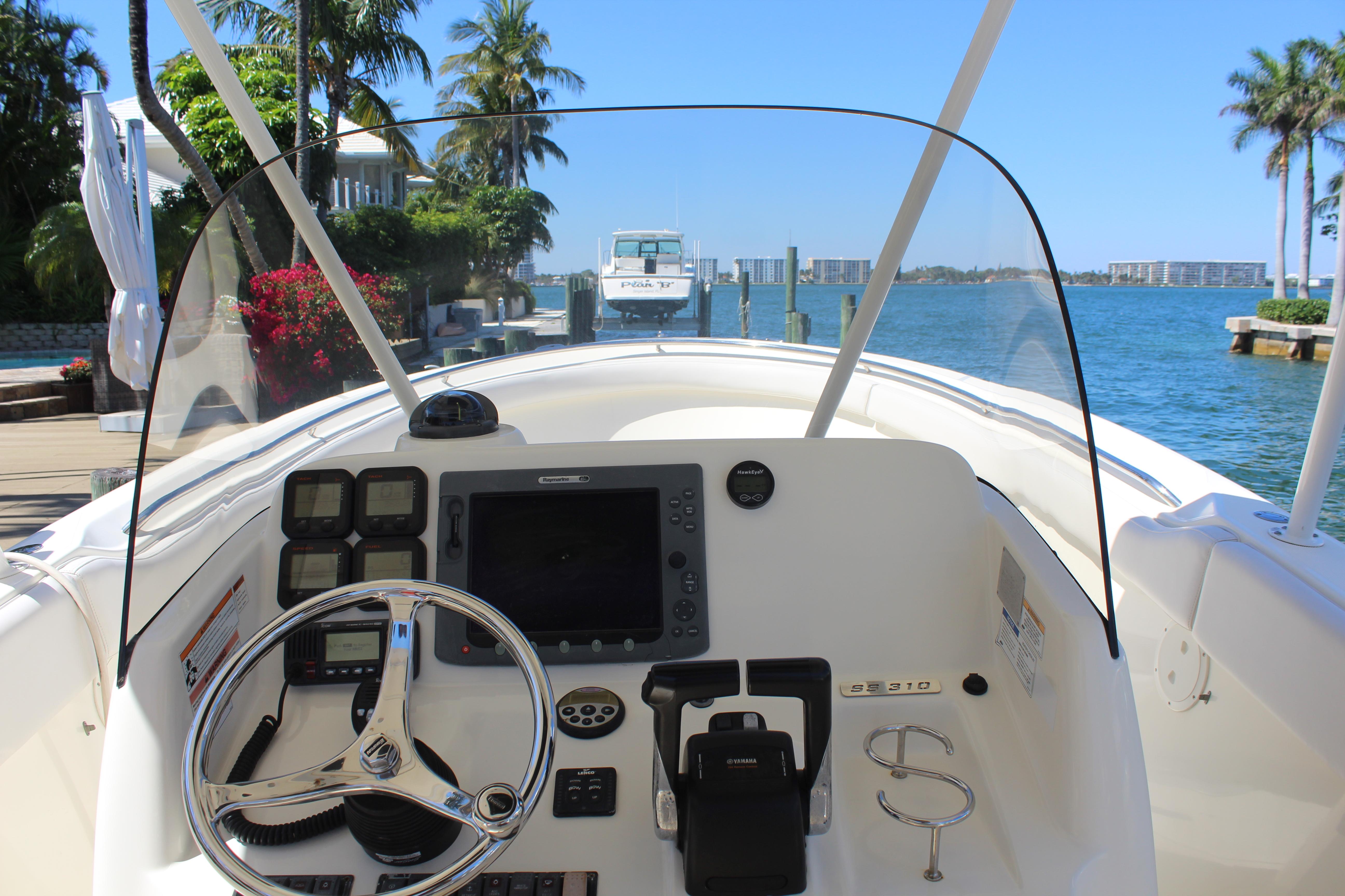 2008 Pursuit S 310 Sport boat dashboard with steering wheel, controls, and waterfront view.