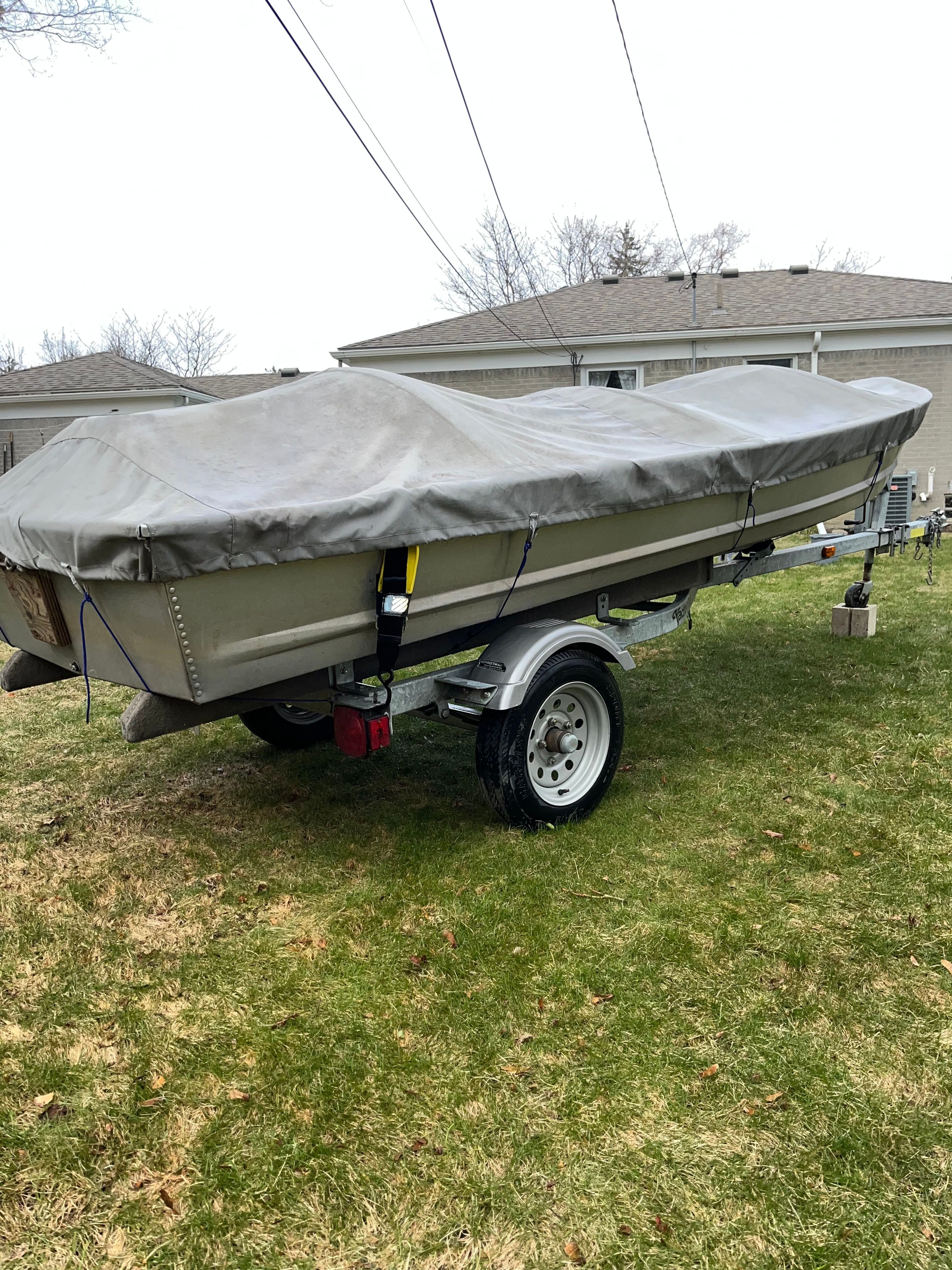 A 2005 Polar Kraft V1460 boat on a trailer in grass, covered with a tarp.