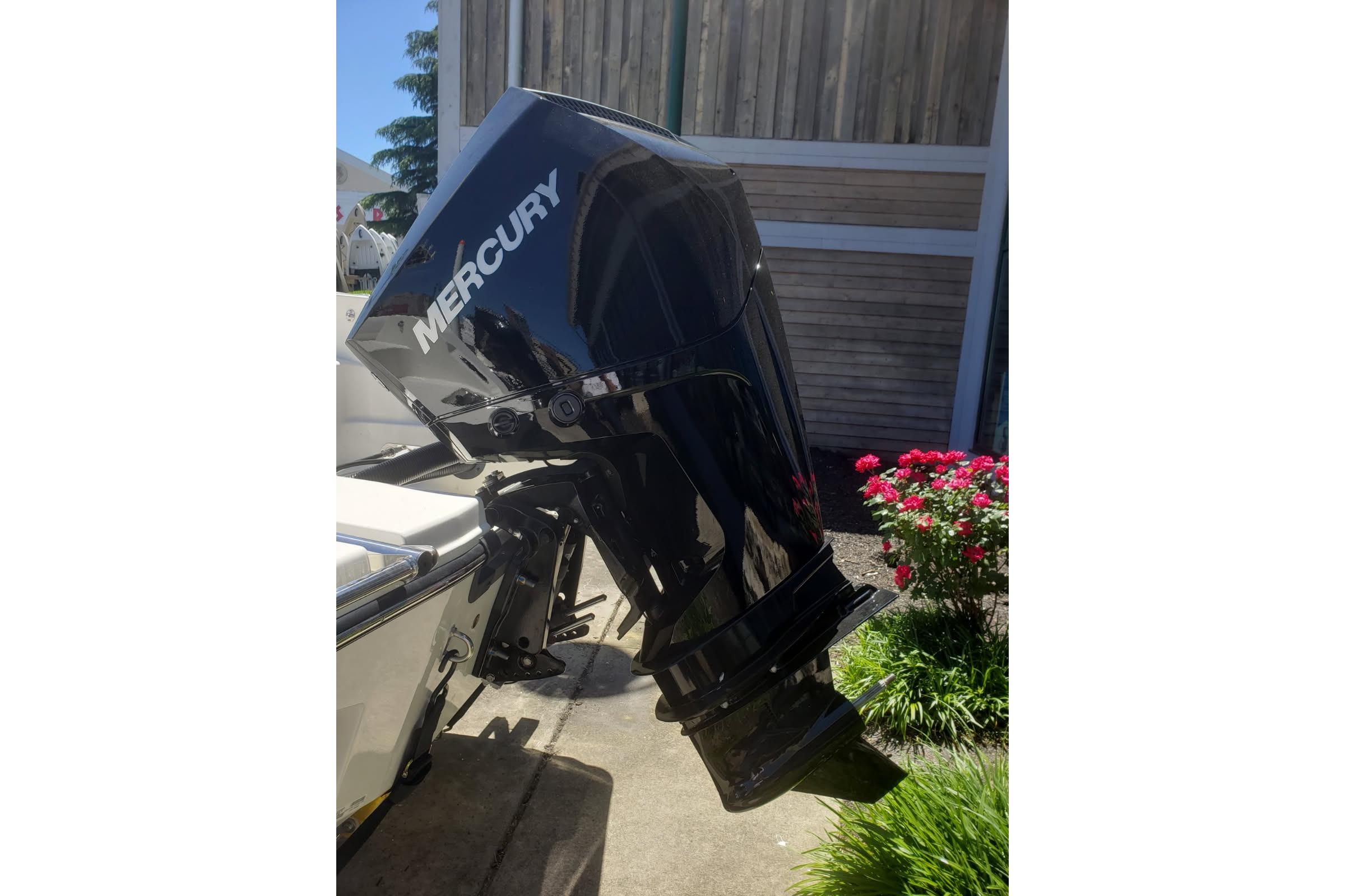 2026 Mako 226 Center Console with Mercury outboard motor, parked near flowers.