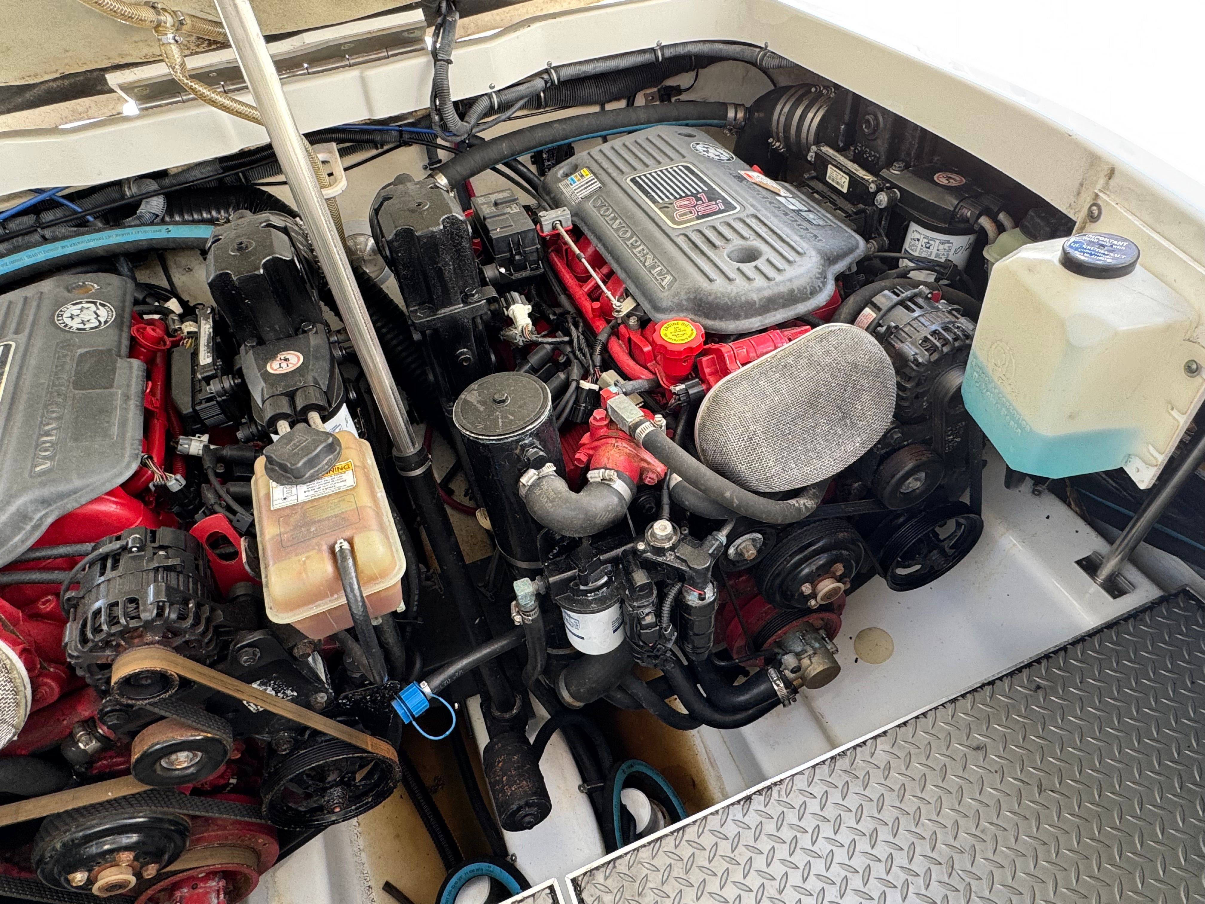 Engine compartment of a boat with two large engines and various hoses.