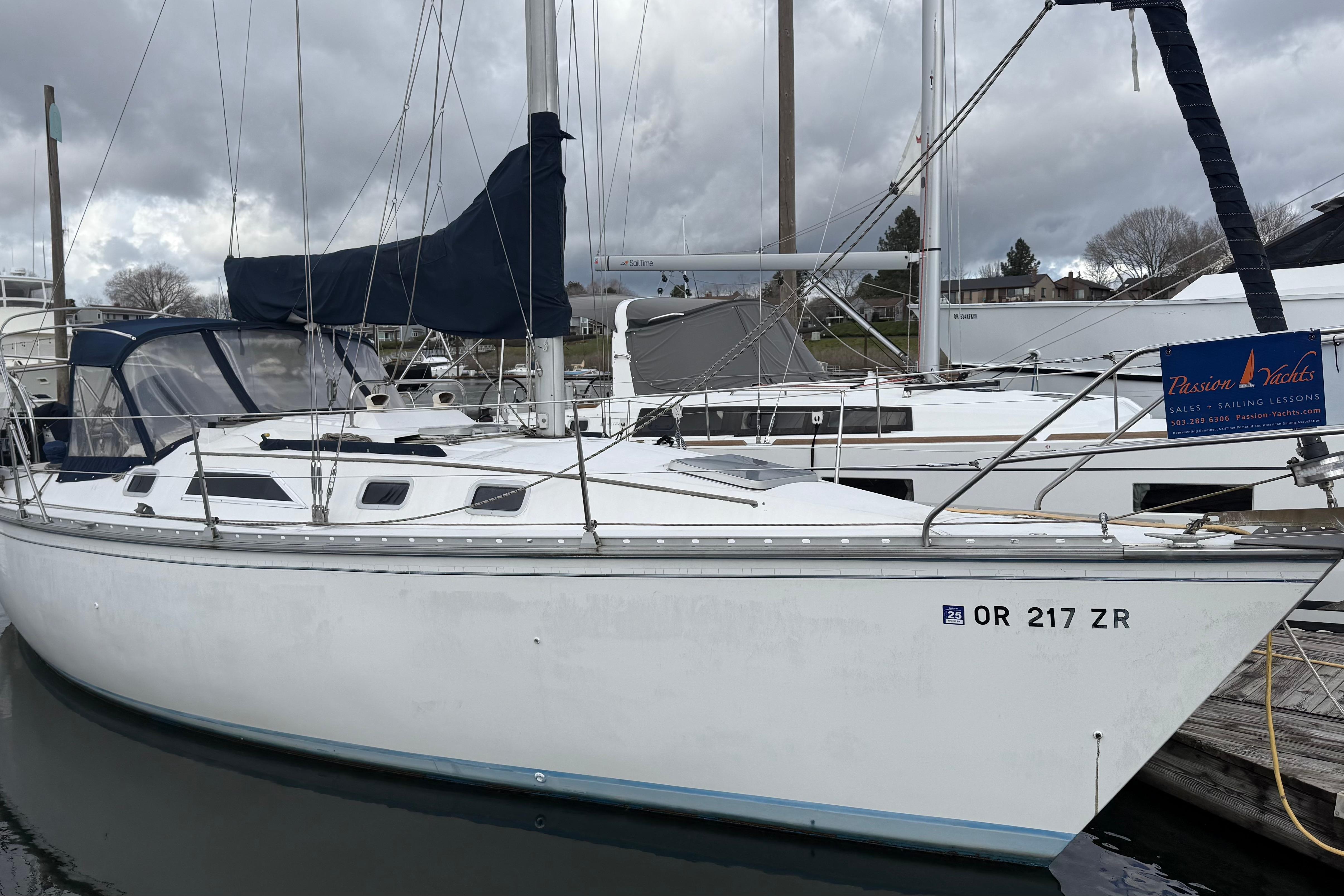 1984 Hunter 31 sailboat docked, featuring white hull and blue canvas cover.