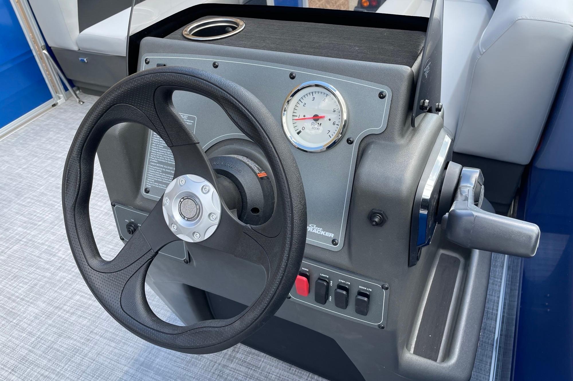 Steering console of 2026 Sun Tracker Party Barge 16 DLX with RPM gauge and controls.