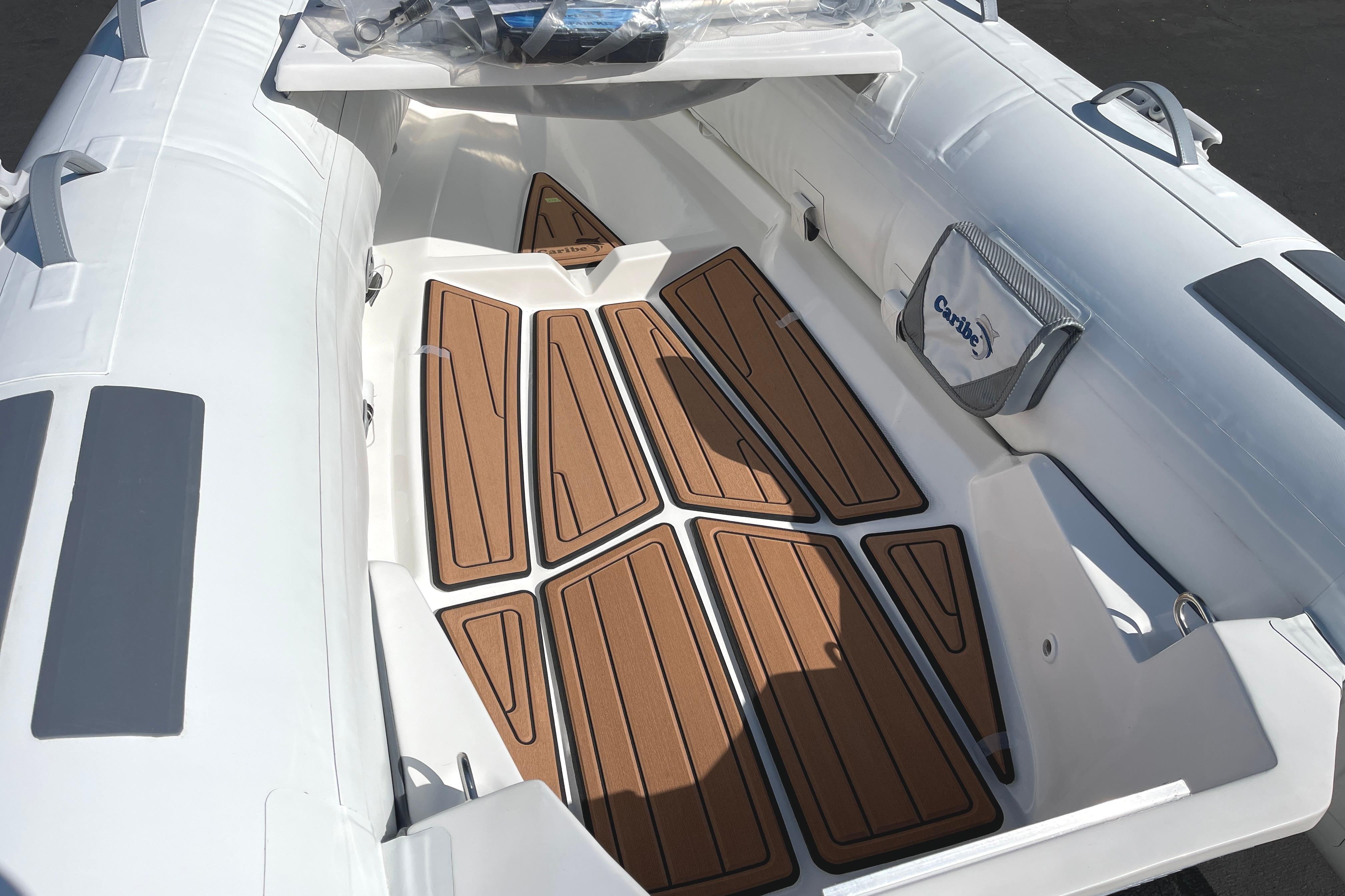2025 Caribe L8 boat interior with teak-style flooring and white seating.