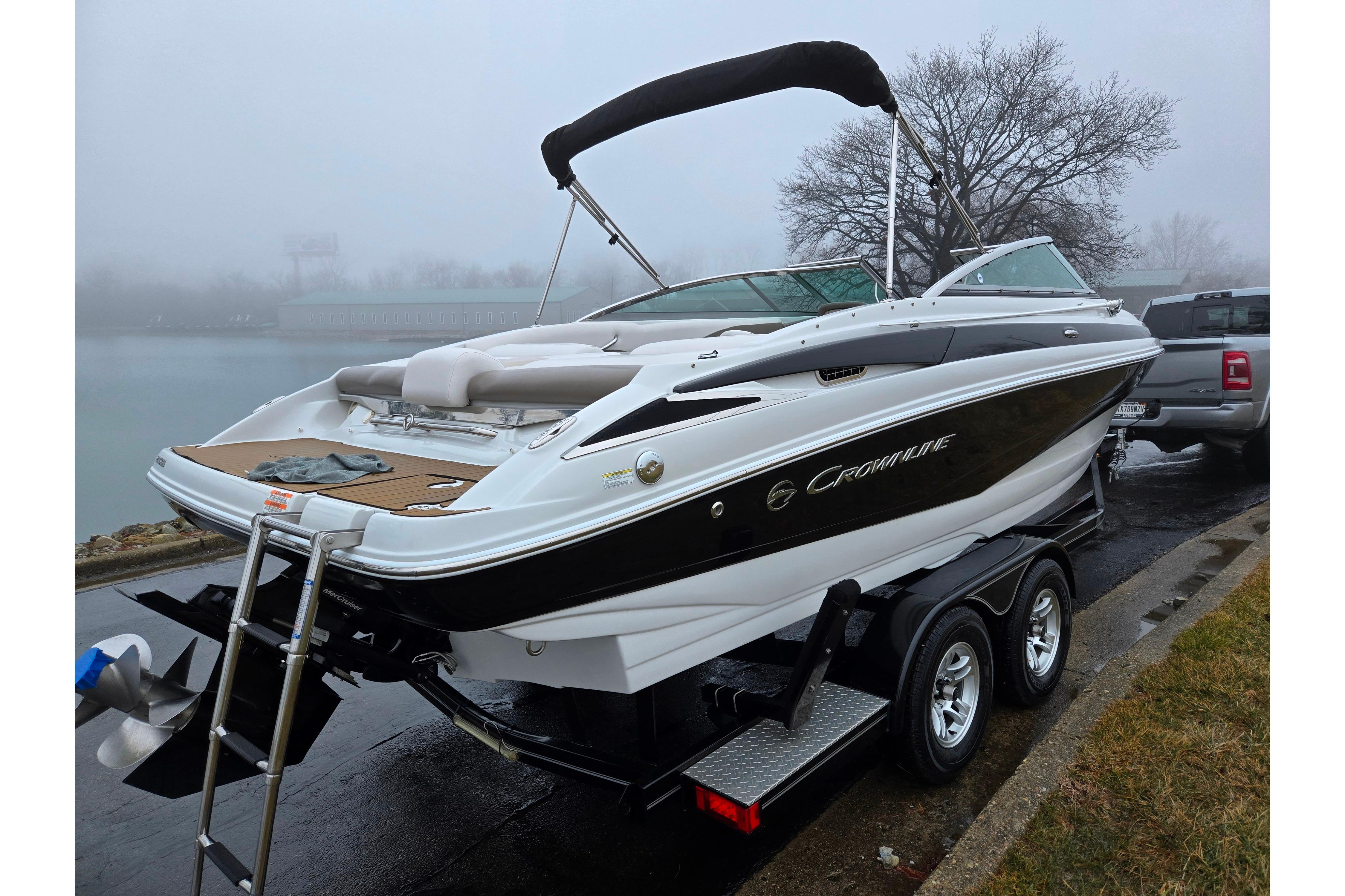 2012 Crownline 235 SS boat on trailer, parked near foggy waterfront.