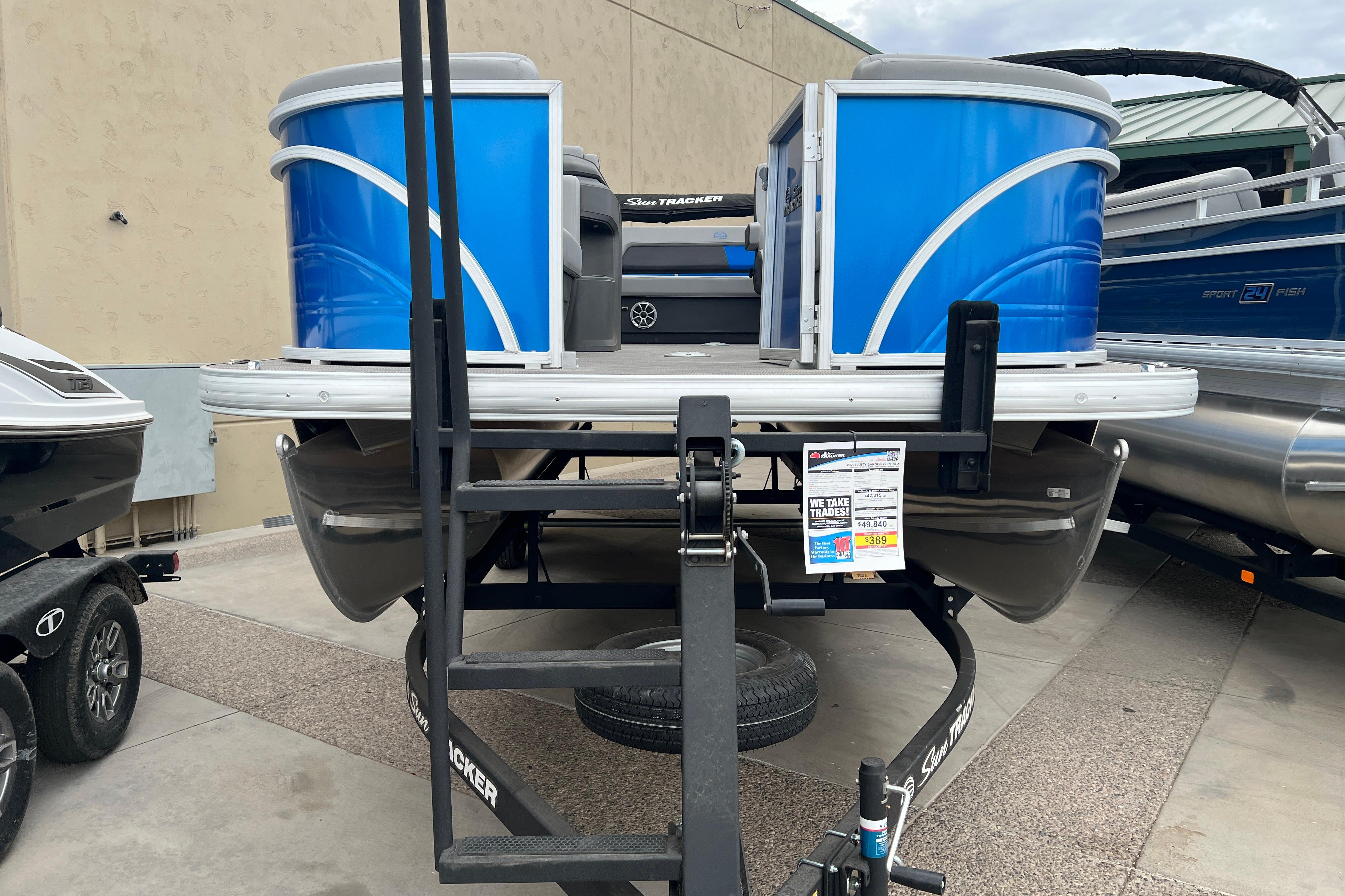 2026 Sun Tracker Party Barge 22 RF DLX pontoon boat on trailer, displayed outdoors.
