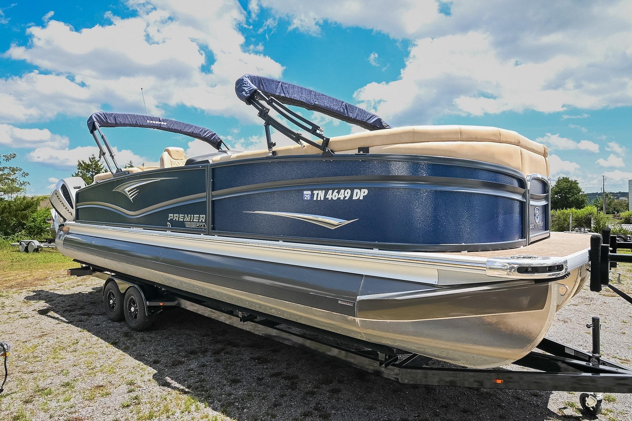 2023 Premier 270 Intrigue RF pontoon boat on trailer under blue sky.