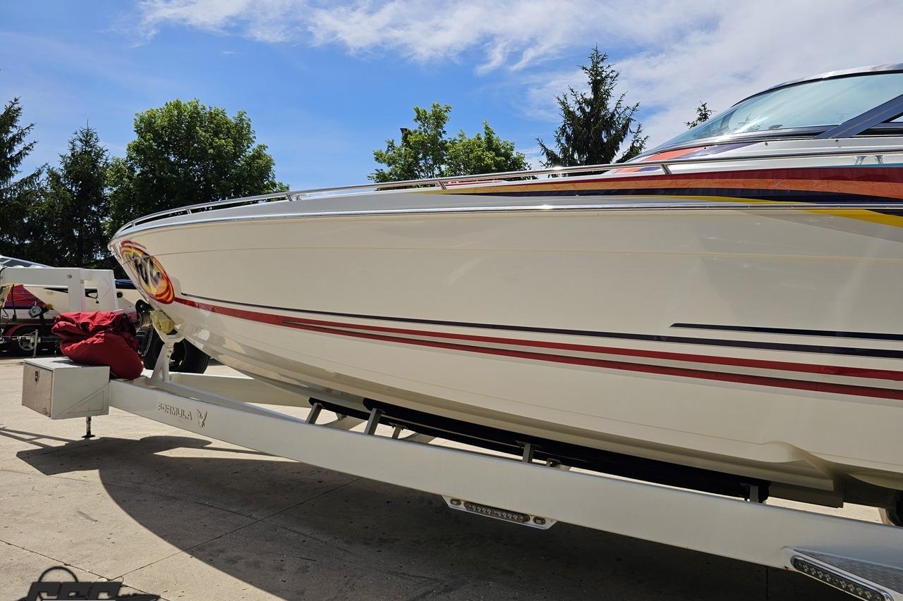 2002 Formula 382 FASTech boat on trailer, vibrant stripes, sunny day.