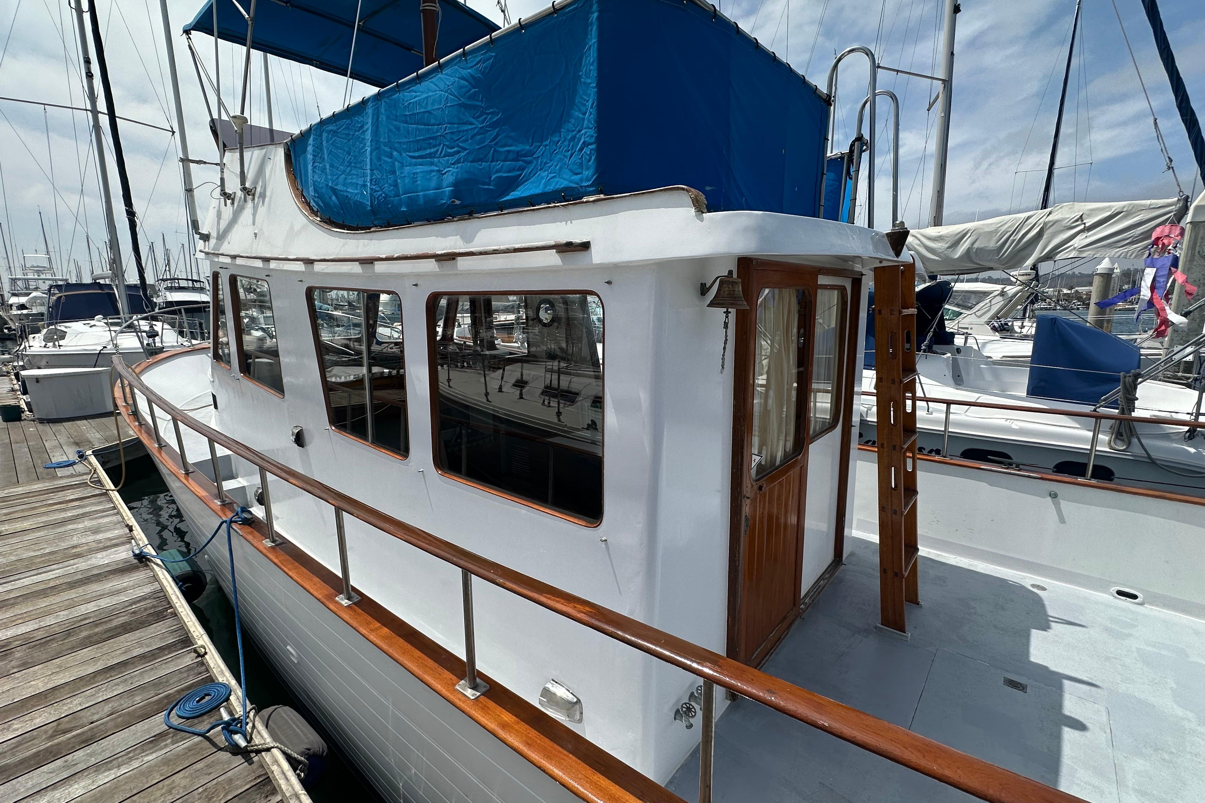 1973 CHB 33 boat docked at marina, featuring wooden railings and blue canopy.