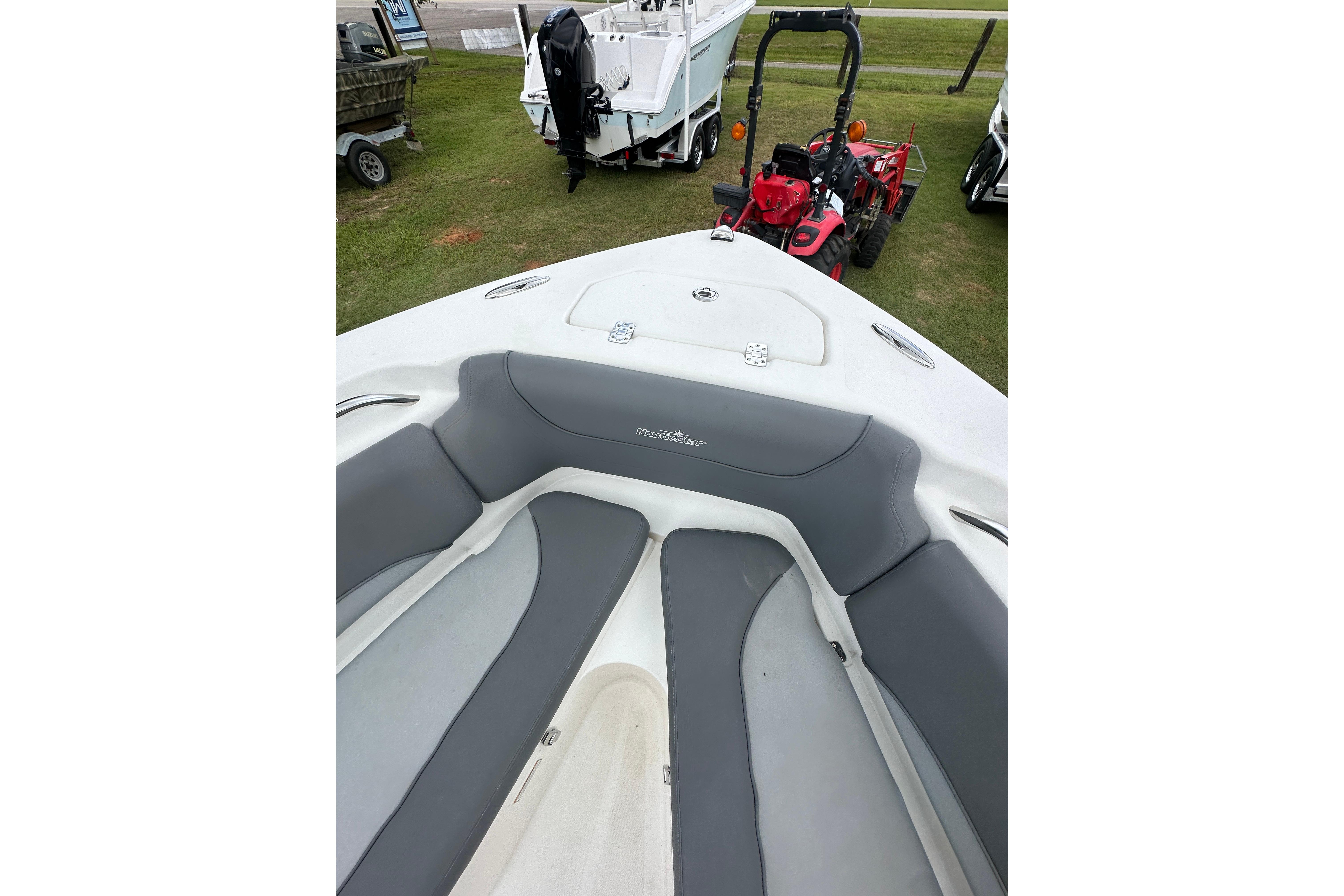 2023 NauticStar 2102 Legacy boat interior with gray seating, parked on grass.