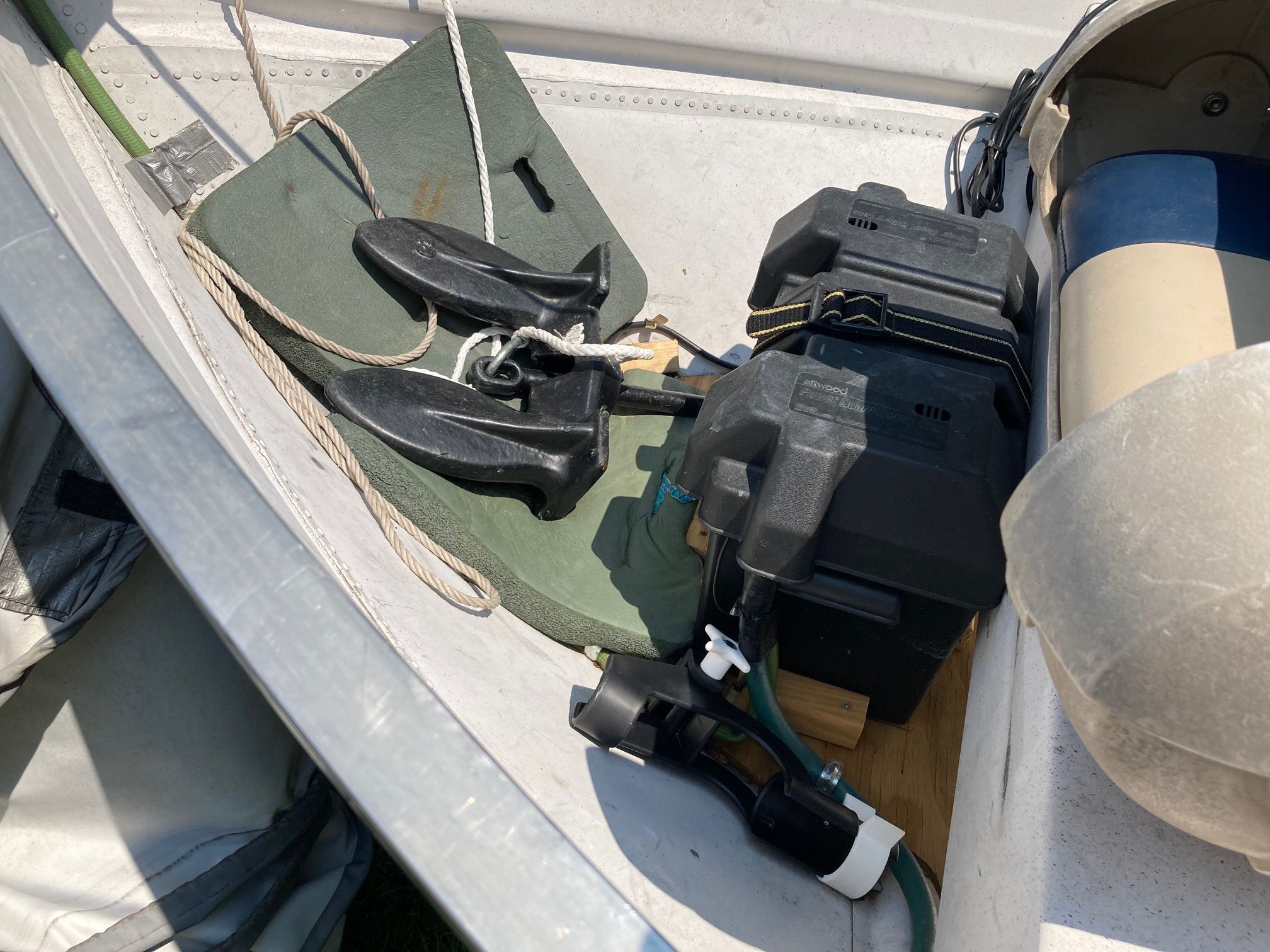 A boat with anchors, batteries, and ropes inside.