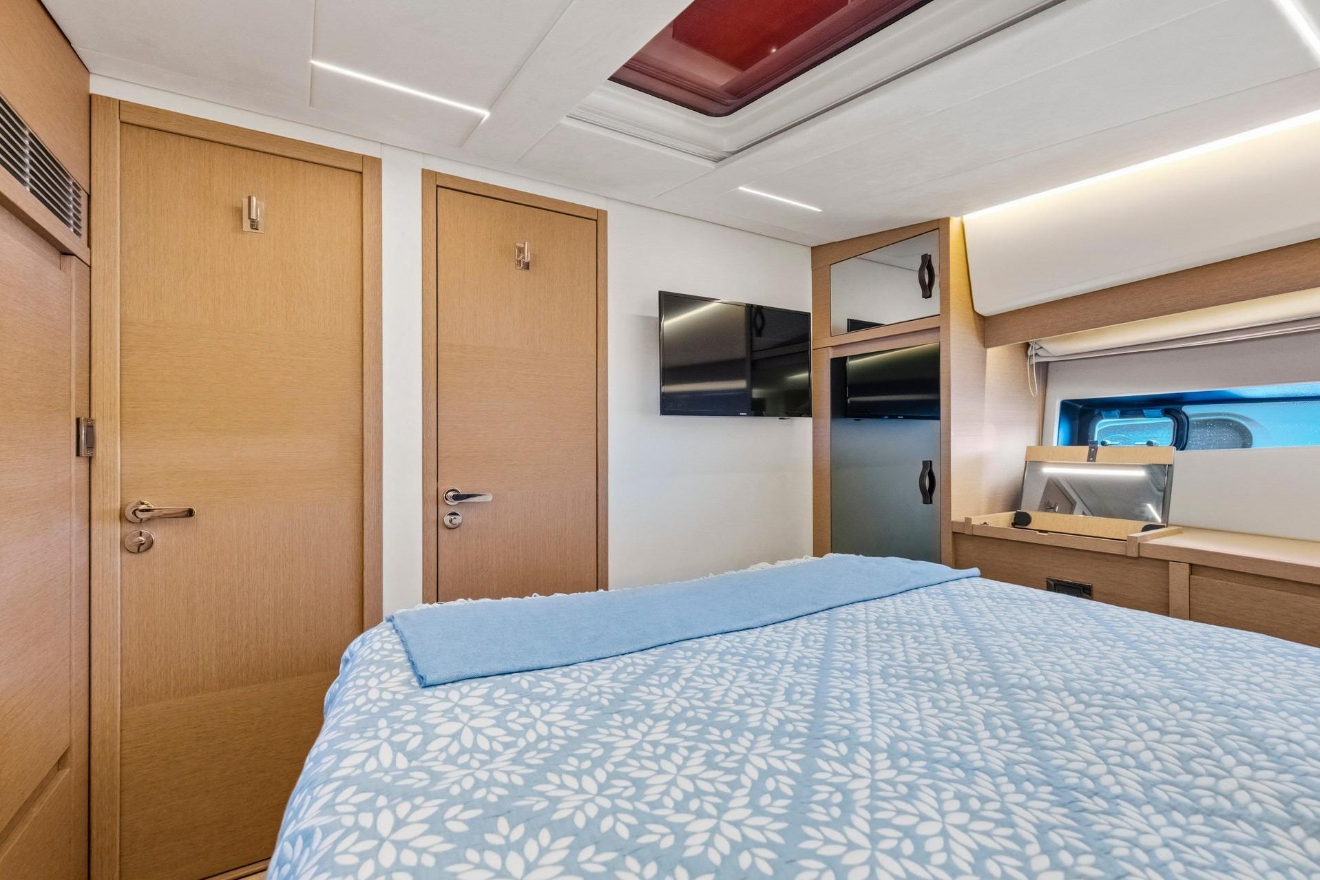 Luxurious bedroom interior of 2022 Prestige 520 yacht with modern design and cozy bedding.