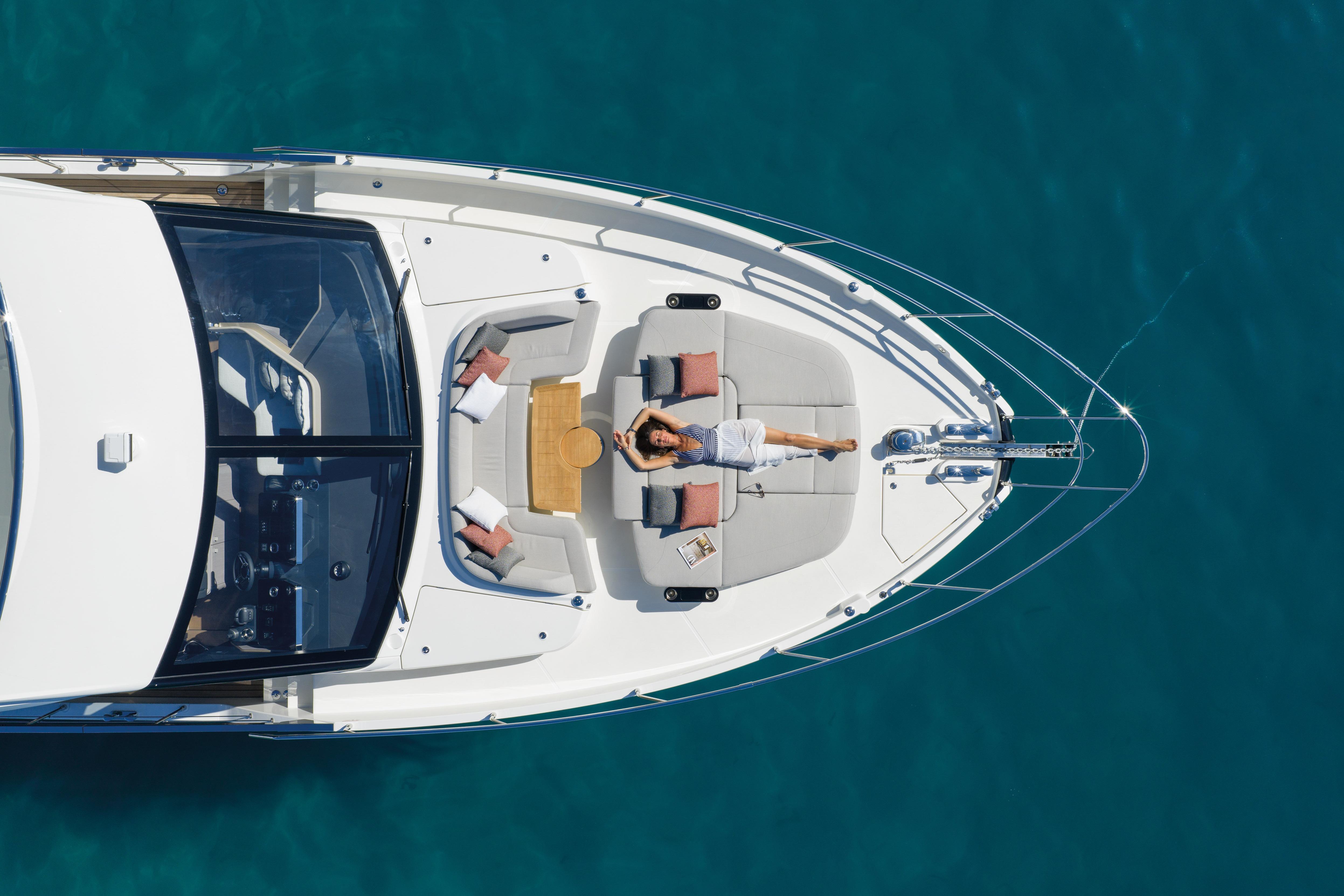 Person relaxing on the deck of a luxury yacht in clear blue water.