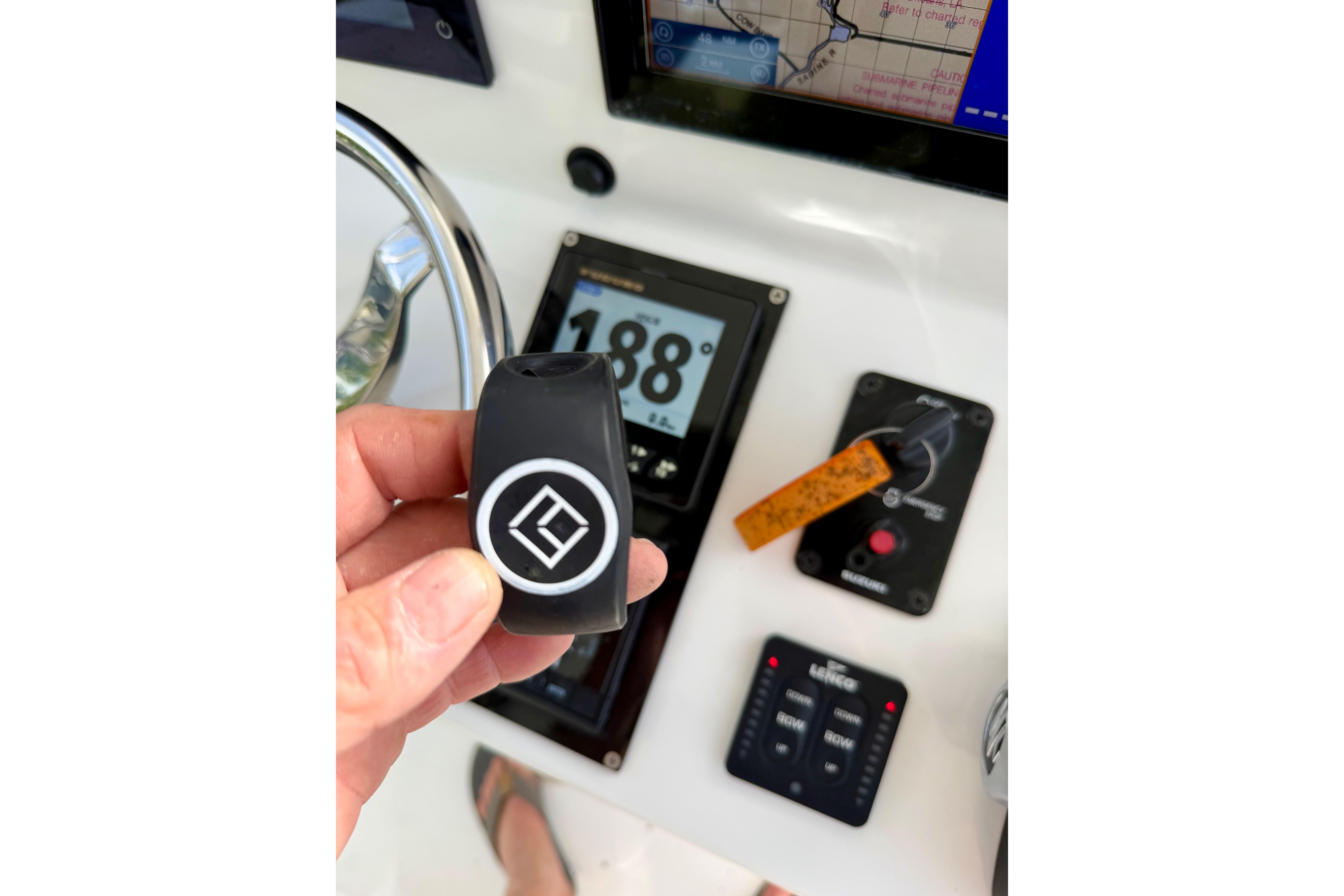 Hand holding a key fob on a 2025 Ocean Master 296 Center Console dashboard.