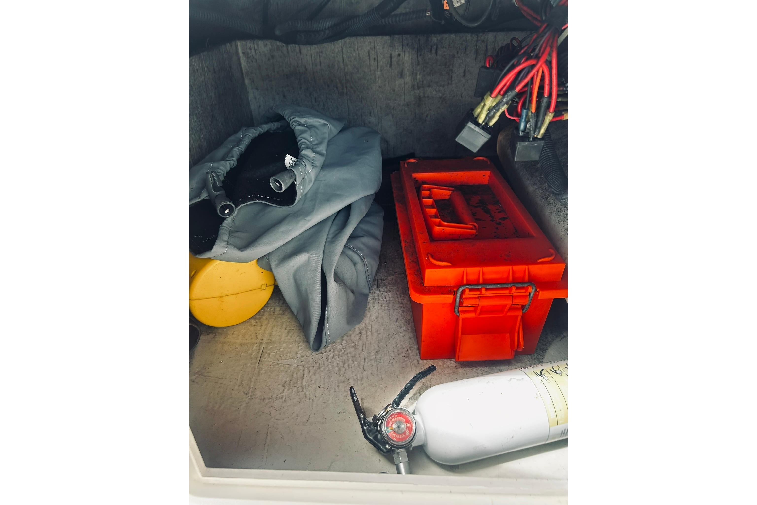 Storage compartment of 2013 Hurricane SunDeck Sport 201 OB with safety gear and tools.