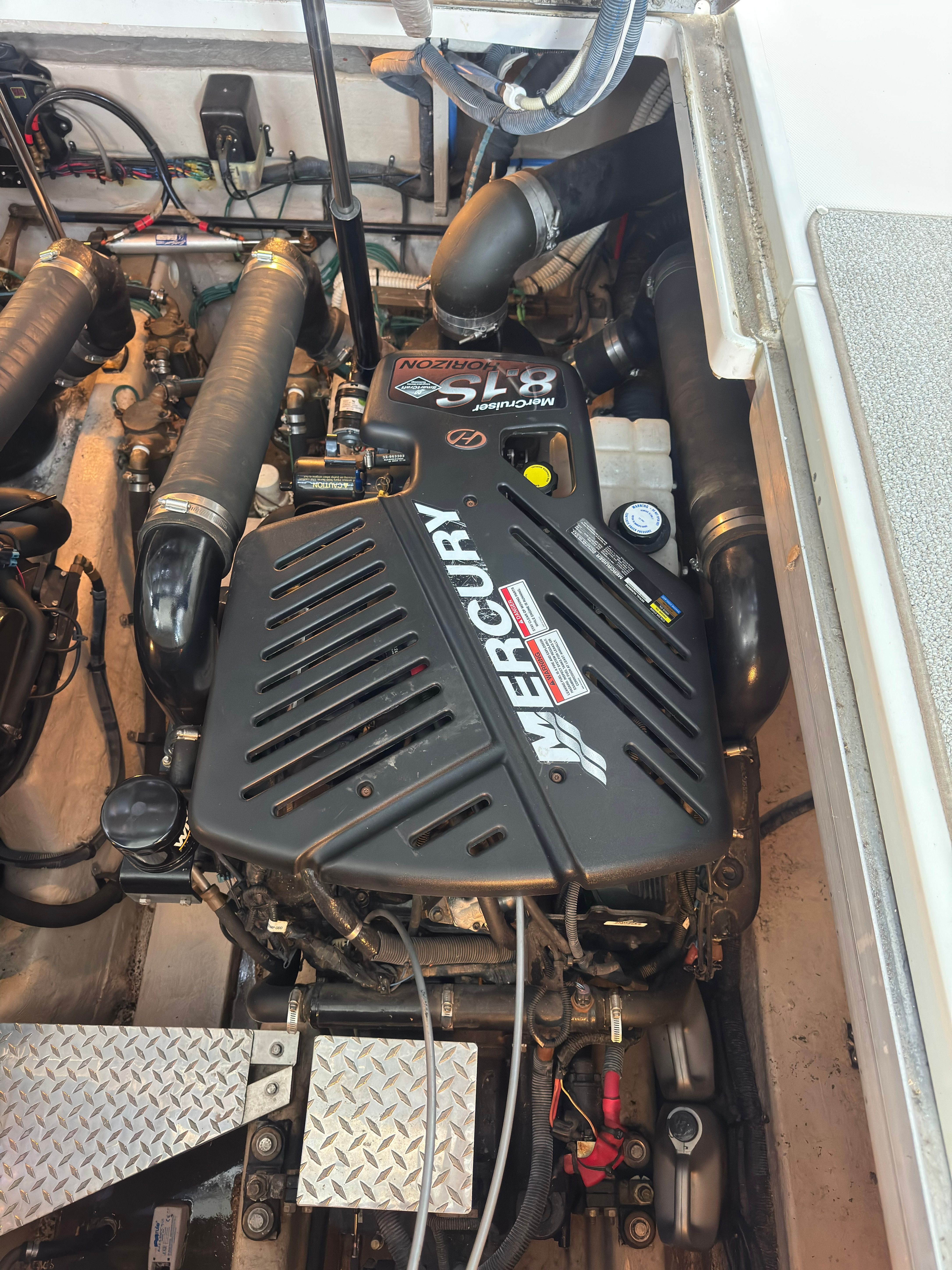 The engine compartment of a 2007 Sea Ray 40 Sundancer shows a Mercury engine with hoses and cables.