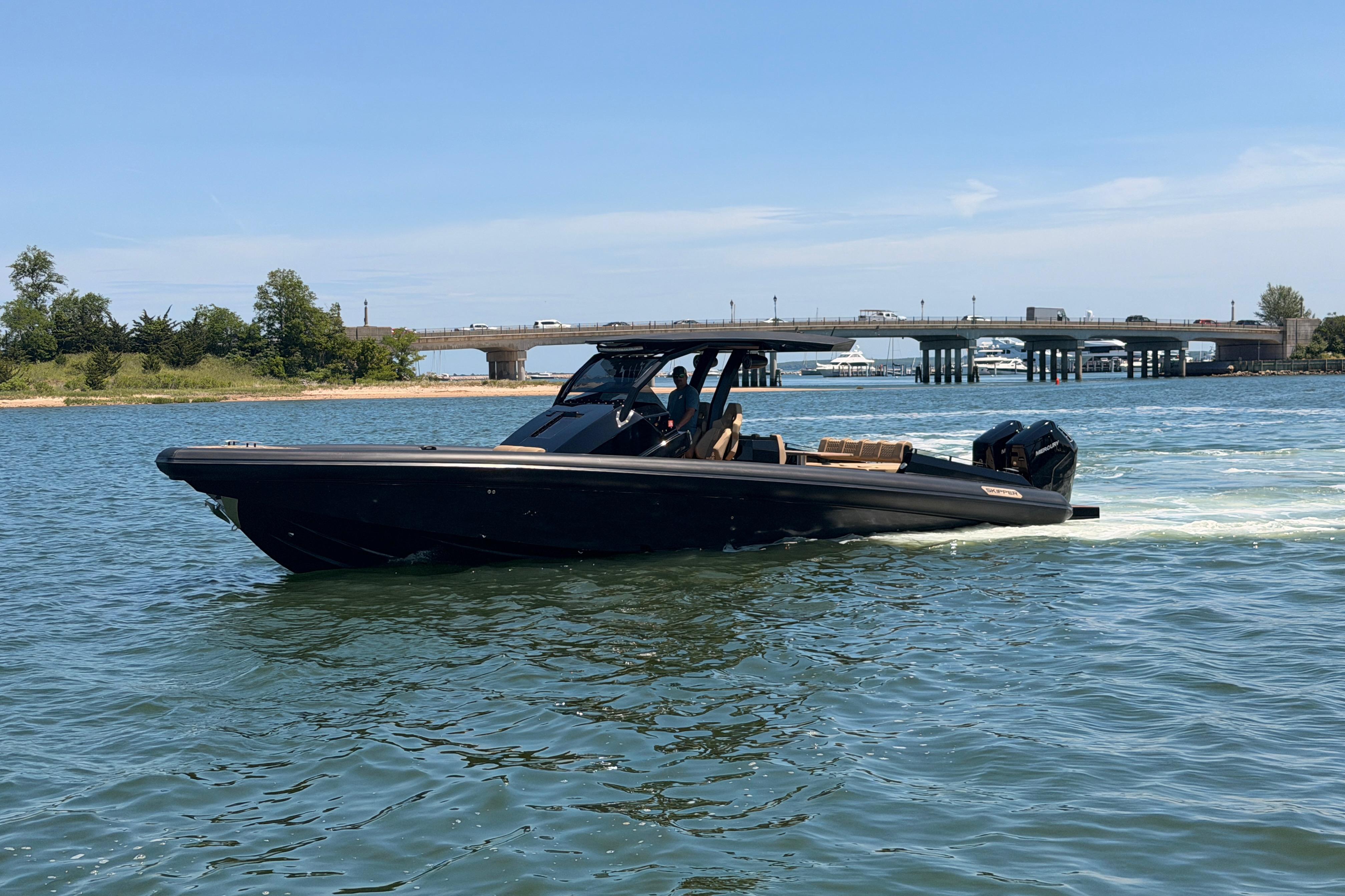 2023 Skipper-BSK 42NC boat cruising on a sunny day near a bridge.