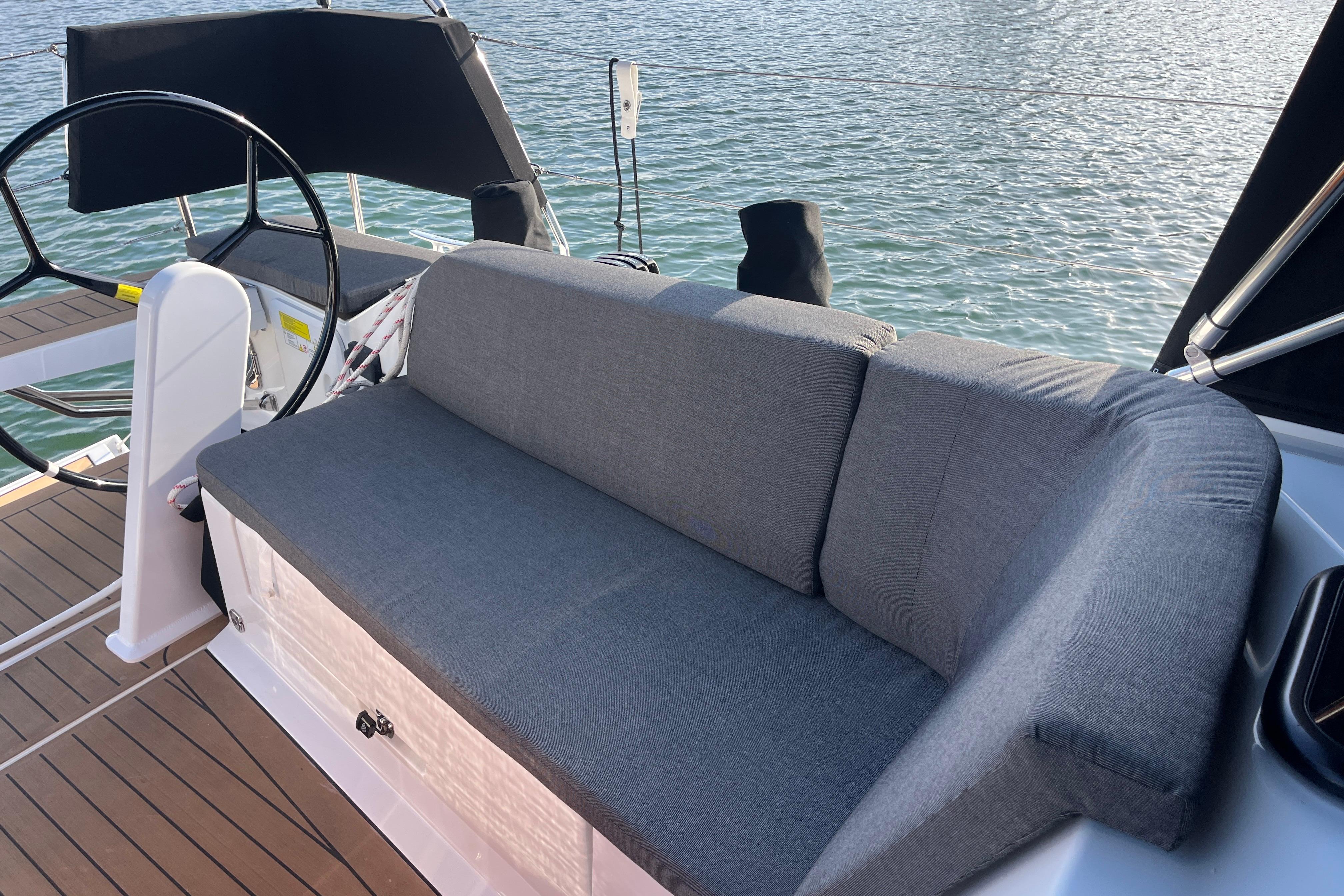 2025 Hanse 360 yacht cockpit with gray cushioned seating and steering wheel.