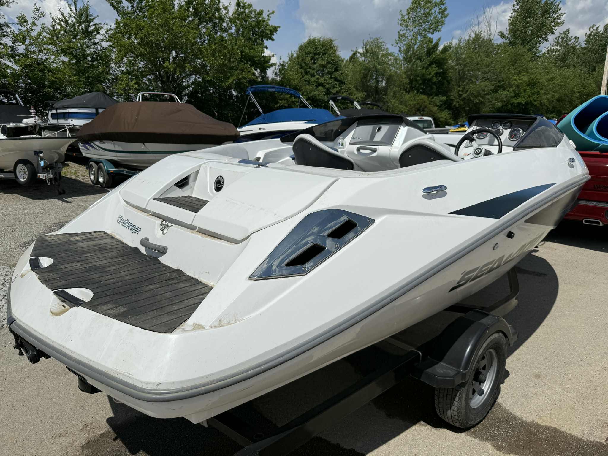 2006 Sea-Doo 180 Challenger boat on trailer, parked outdoors with other boats.