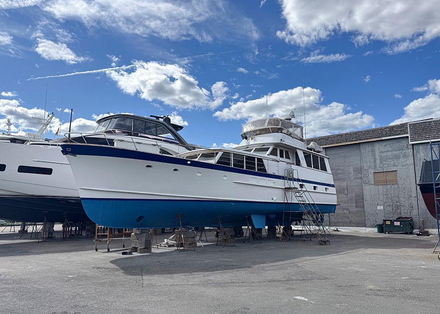 A 1961 Burger 63 yacht is on a dry dock under a blue sky.