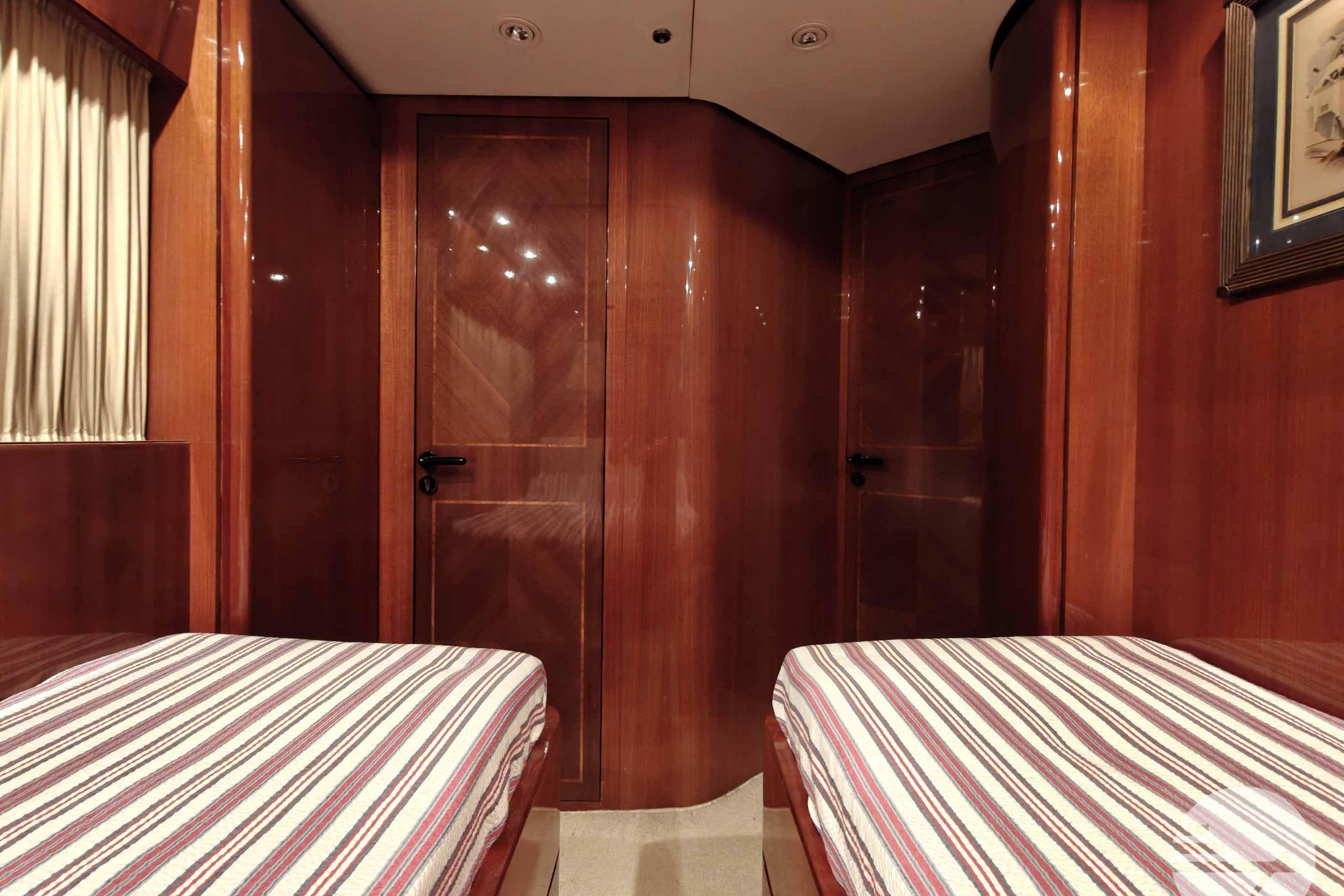 Luxurious Sanlorenzo SL82 yacht cabin interior with twin beds, wood paneling, and elegant decor.