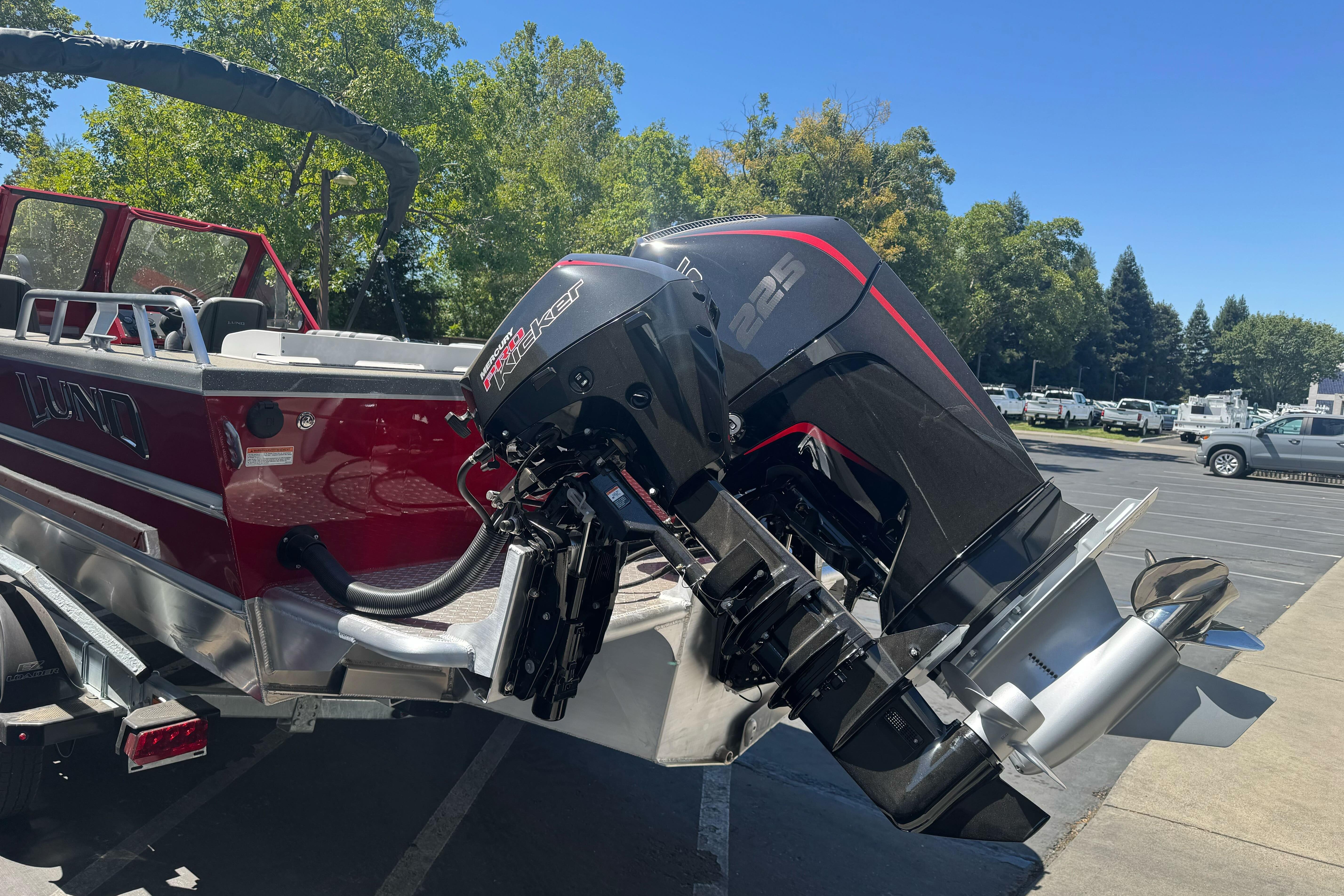 2026 Lund 210 Heavy Gauge boat with powerful outboard motor in a parking lot.